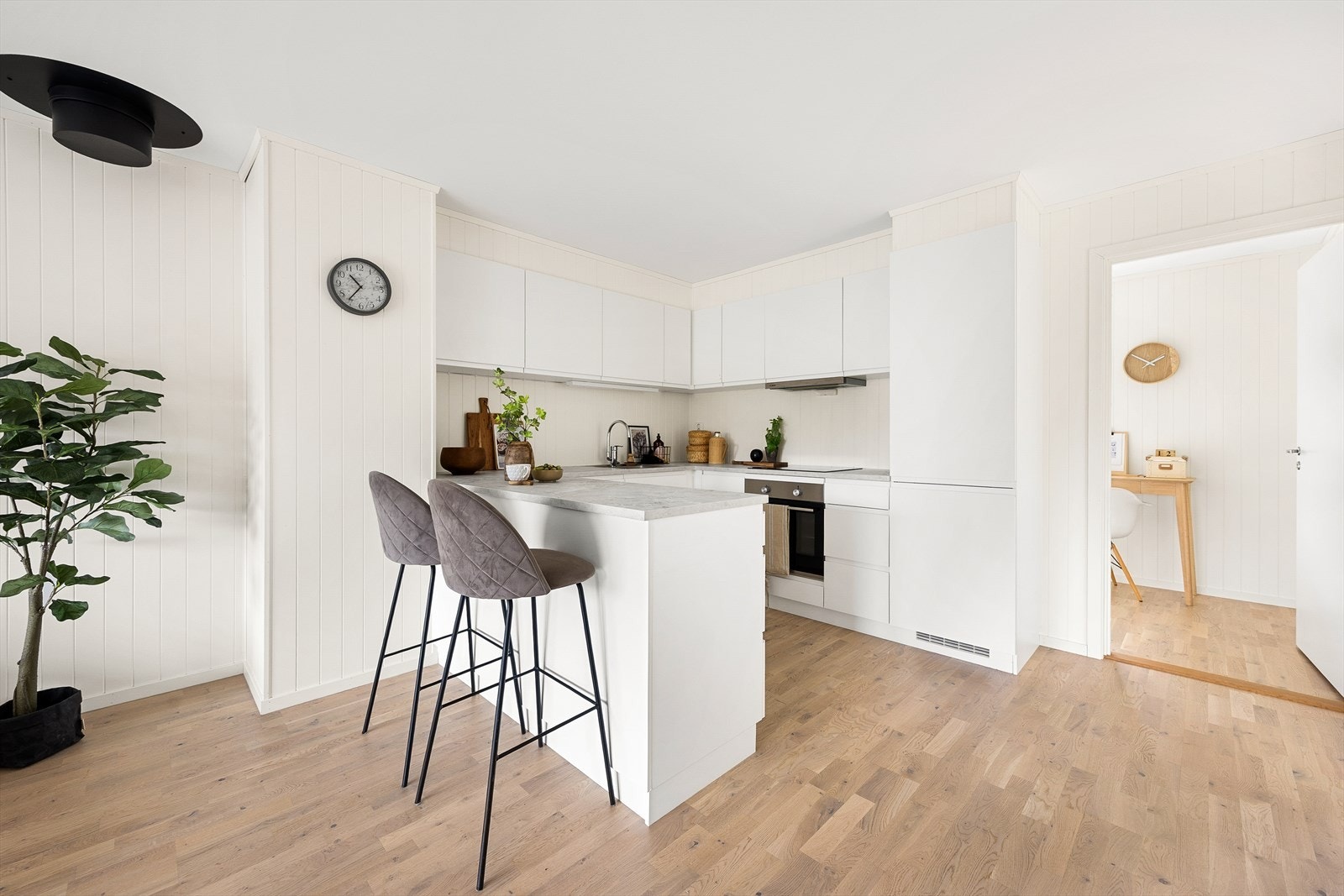 Den åpne løsningen med halvøy gjør kjøkkenet til en sosial sone i leiligheten. Galleribilde