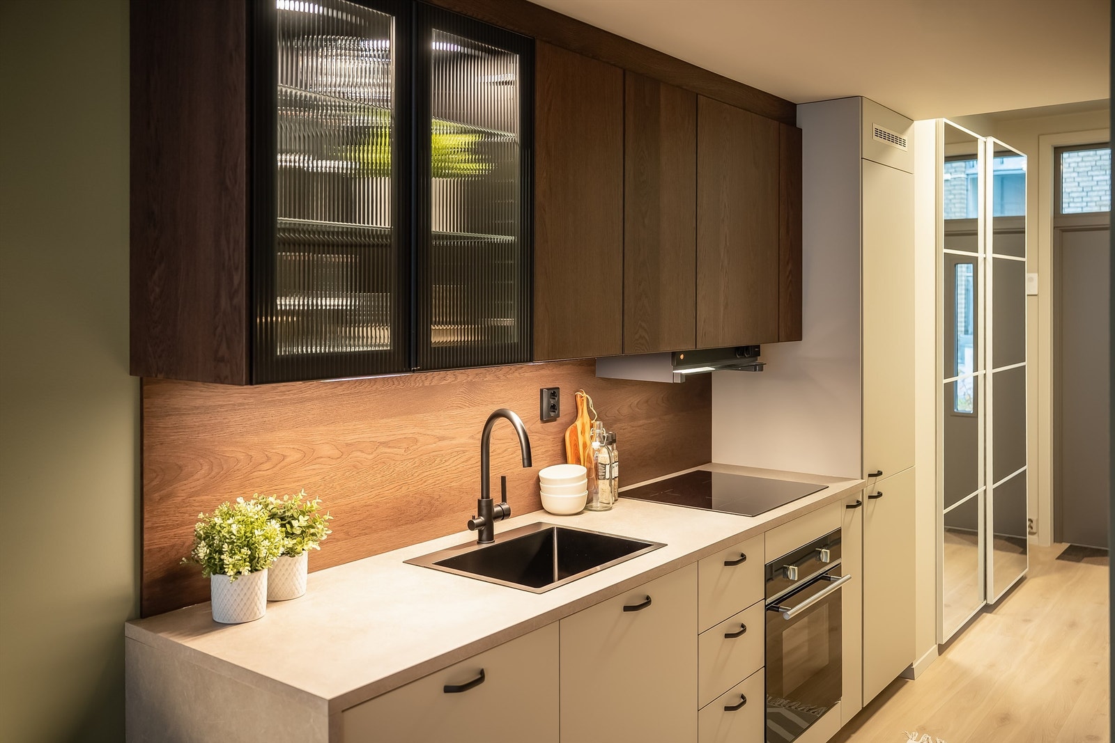 Kjøkkeninnredningen har også et vitrineskap med integrert belysning og glassdører Galleribilde