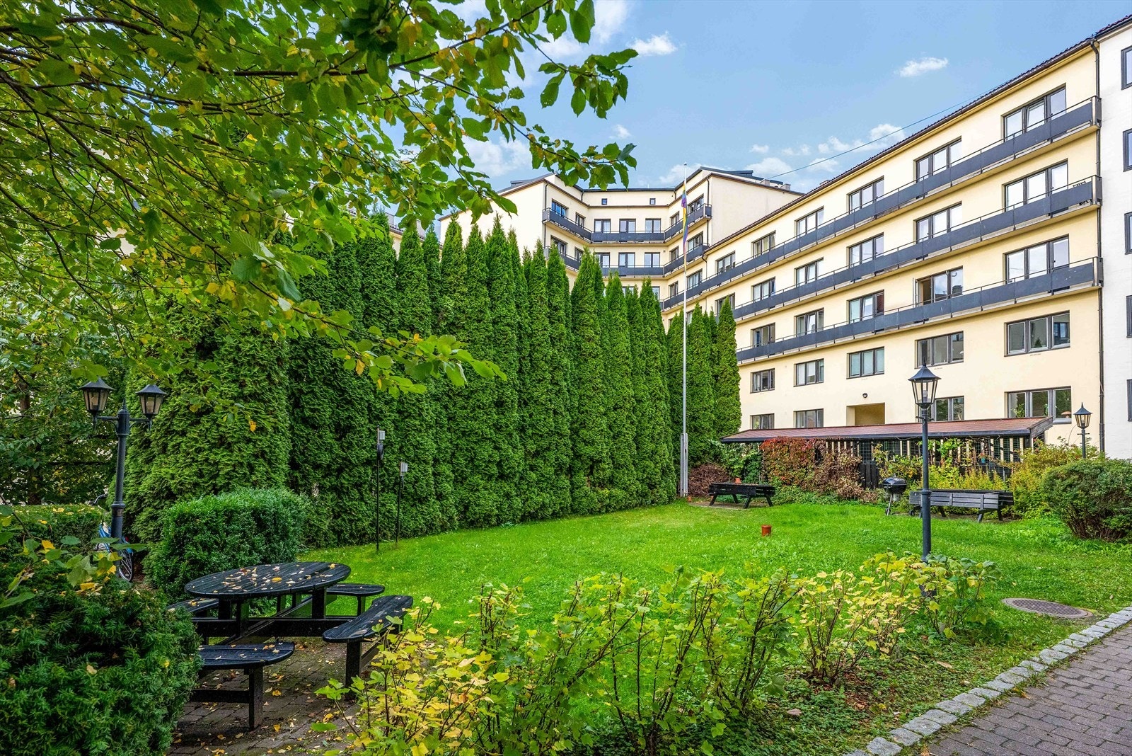 Velholdt hage med busker og sitteplasser innbyr til sosialt samvær. Galleribilde