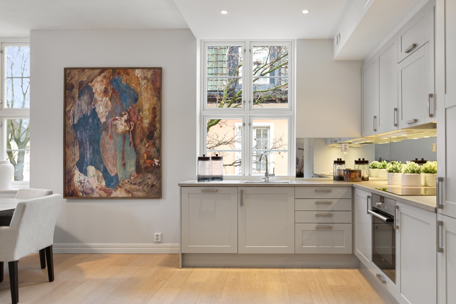 Benkeplaten er utført i slitesterk laminat, og arbeidssonen er utstyrt med oppvaskkum samt speilfelt over benken, noe som bidrar til både romfølelse og et moderne preg. Galleribilde