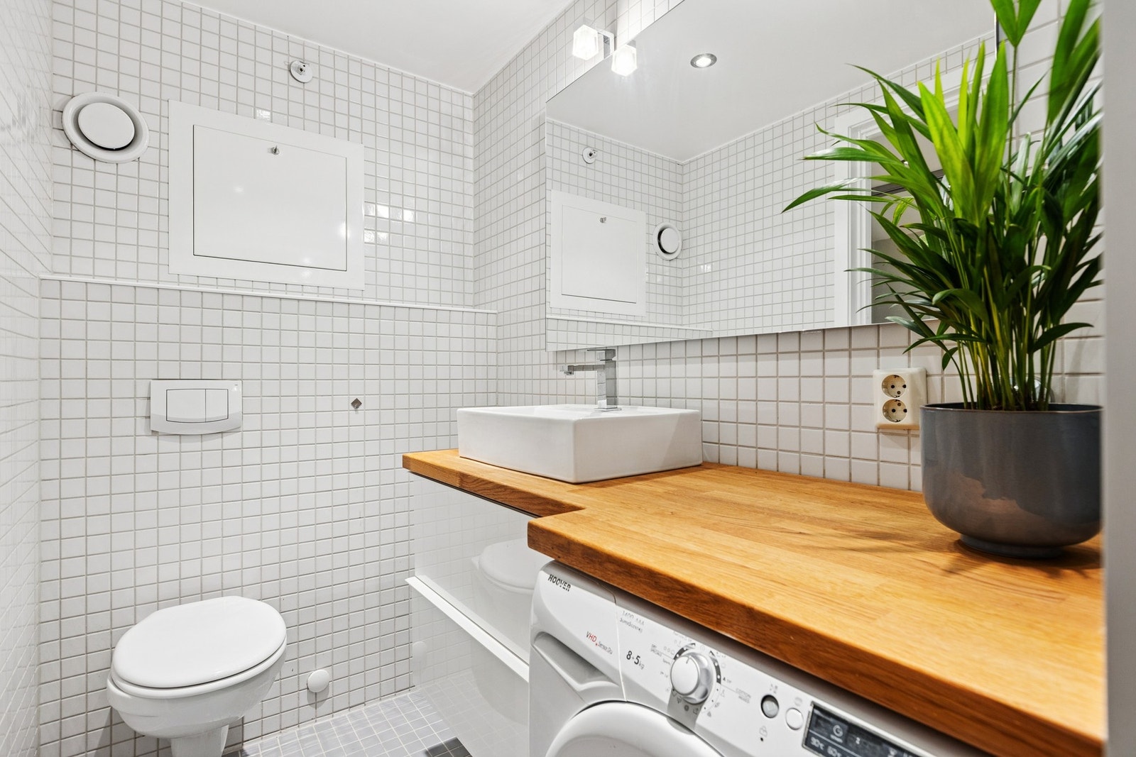 Badet er lyst og flislagt med innbydende innredning, dusjhjørne og plass til vaskemaskin. Galleribilde