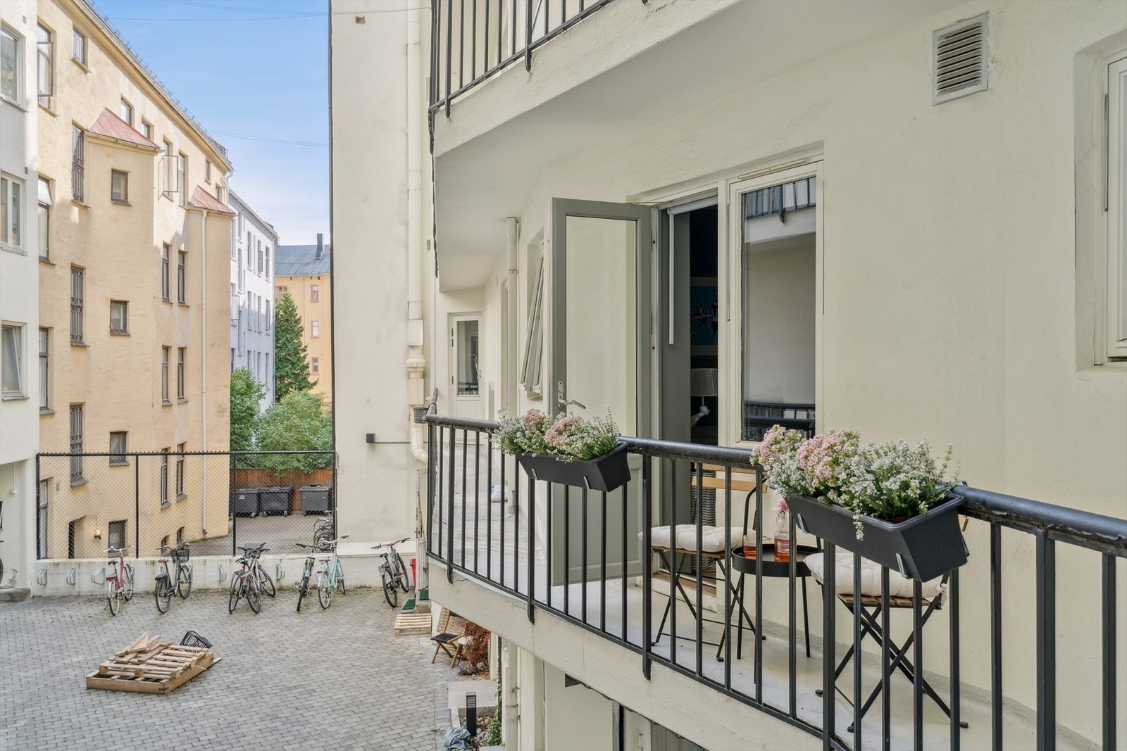 Brannbalkongen vender ut mot en rolig bakgård med felles sykkelparkering. (Sommerbilde) Galleribilde