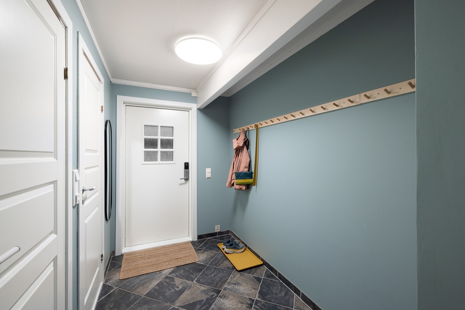 Velkommen inn i en romslig entré med god plass til oppbevaring av yttertøy. Det er montert kodelås på ytterdøren for en enklere og nøkkelfri hverdag. Galleribilde