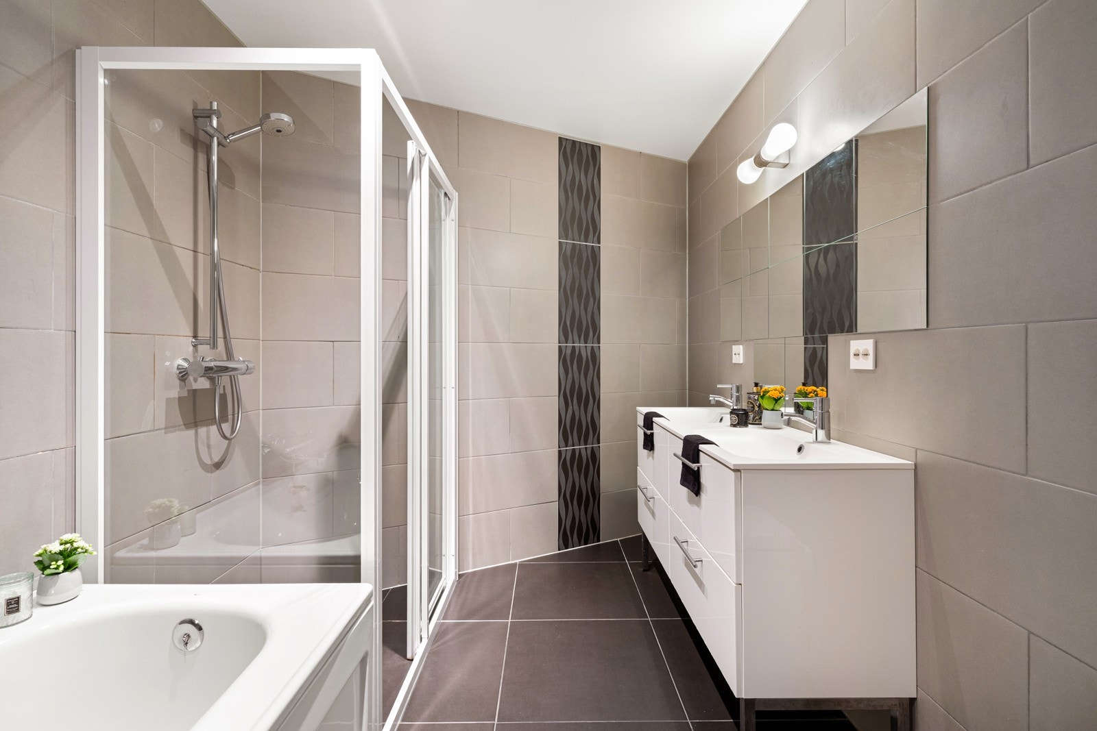 Begge badene er helflisede og gjennomført elegante, med moderne innredning og tidløse materialvalg. Galleribilde