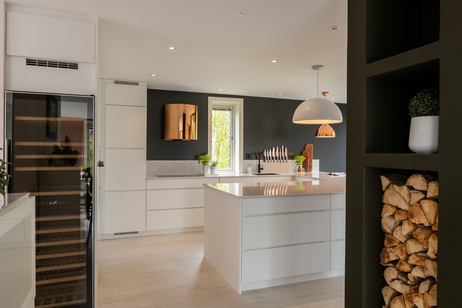 Stuearealet og kjøkkenet ligger i et sosialt og åpent allrom som er naturlig delt av pipeløpet og ildstedene sentrert i denne delen av huset. Galleribilde