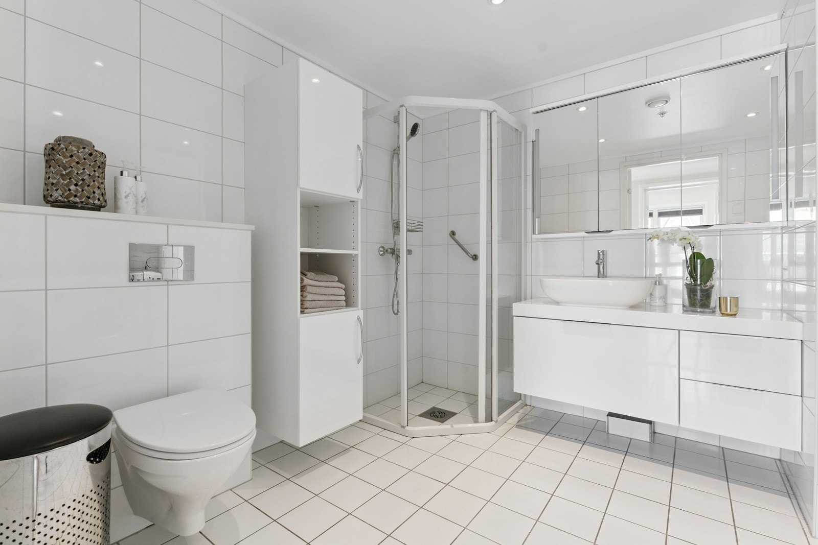 Romsleg og pent flislagt bad. Moderne innreiing med stilfull vask og praktisk speilskap Galleribilde