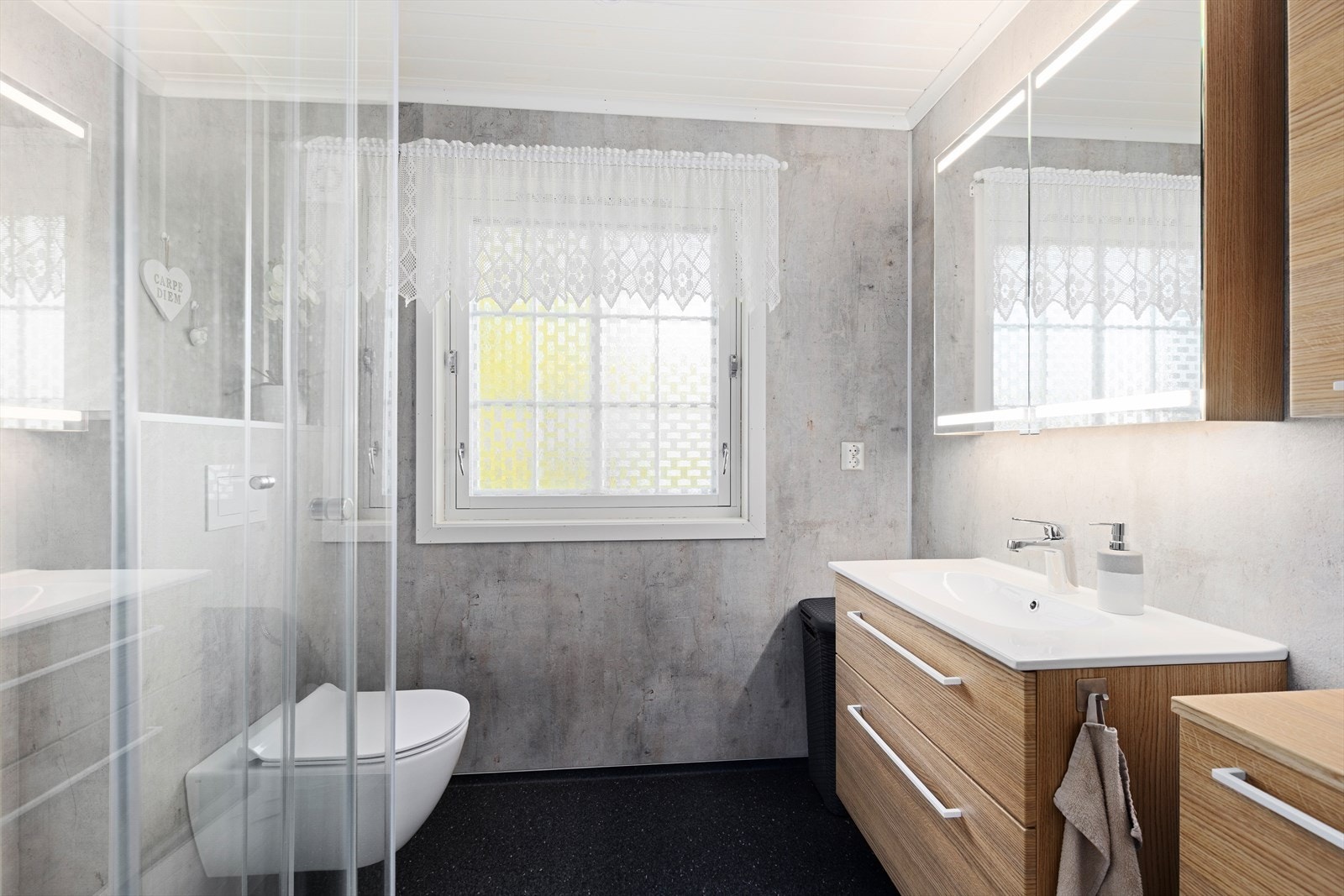 Bad i hovedetasjen med vinylbelegg på gulv, baderomsplater på vegger og trepanel i tak. Badet er innredet med nedfelt servant, veggmontert toalett og dusjkabinett. Avtrekk via elektrisk, fuktstyrt vifte i yttervegg. Galleribilde