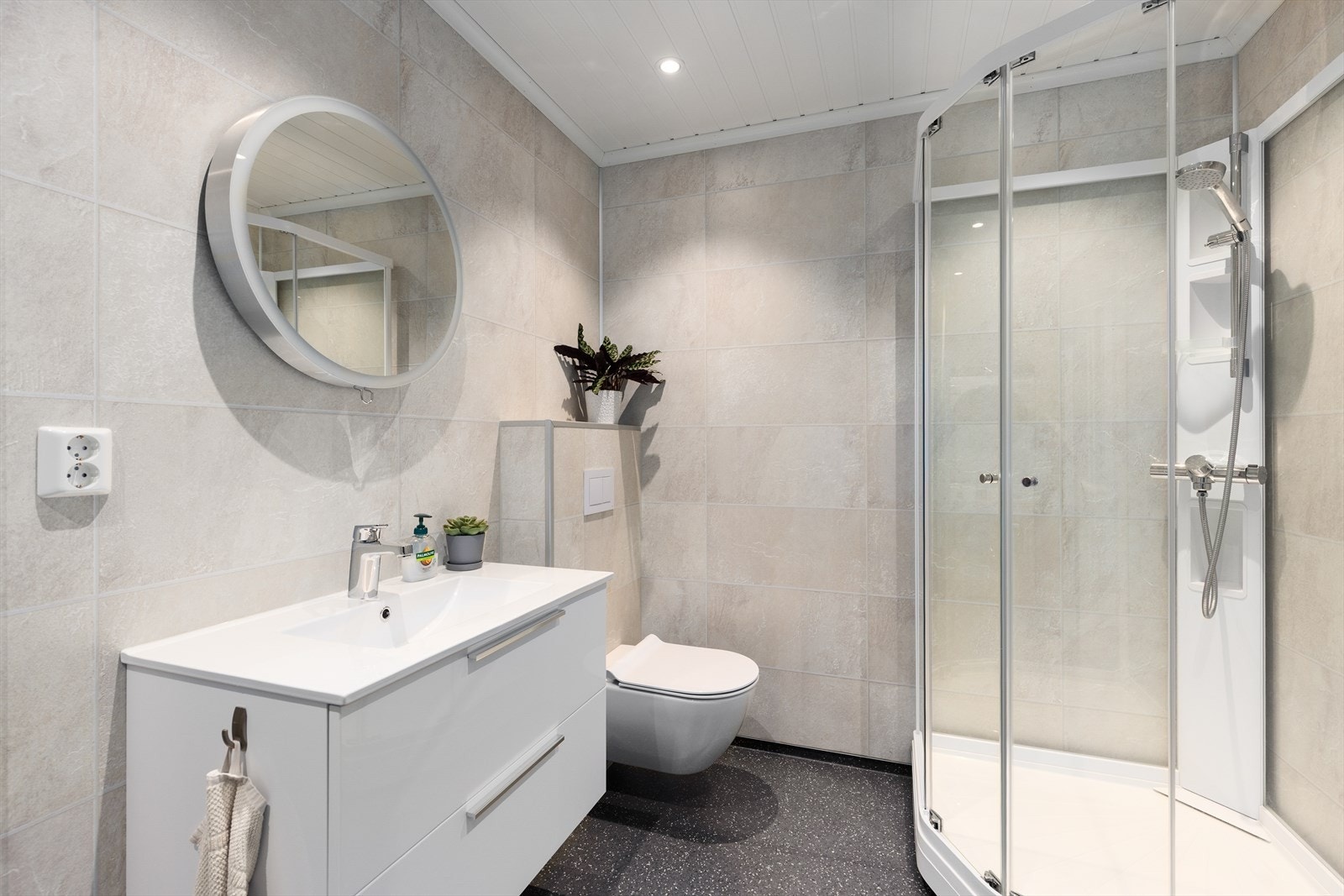 Bad/vaskerom i underetasjen med vinylbelegg på gulv og varmekabler. Baderomsplater på vegger og trepanel i tak. Galleribilde