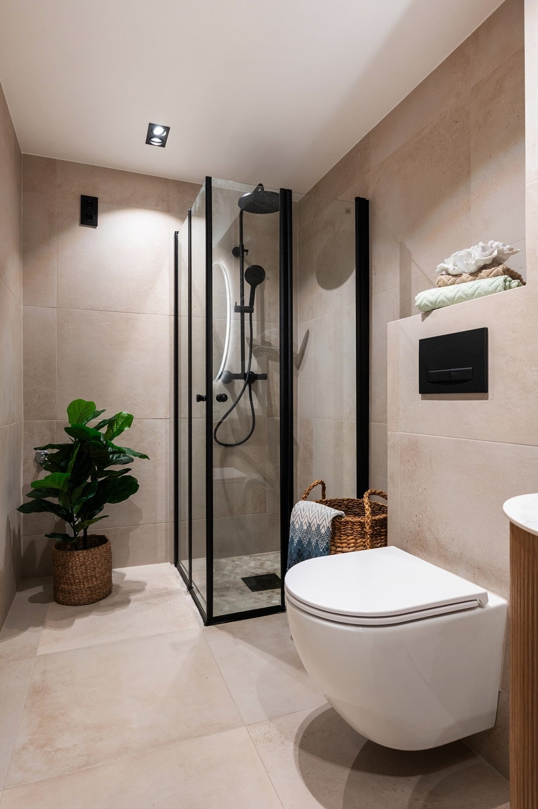 Dusjhjørne med innfellbare dører i sort profil og vegghengt toalett for enkel rengjøring. Galleribilde