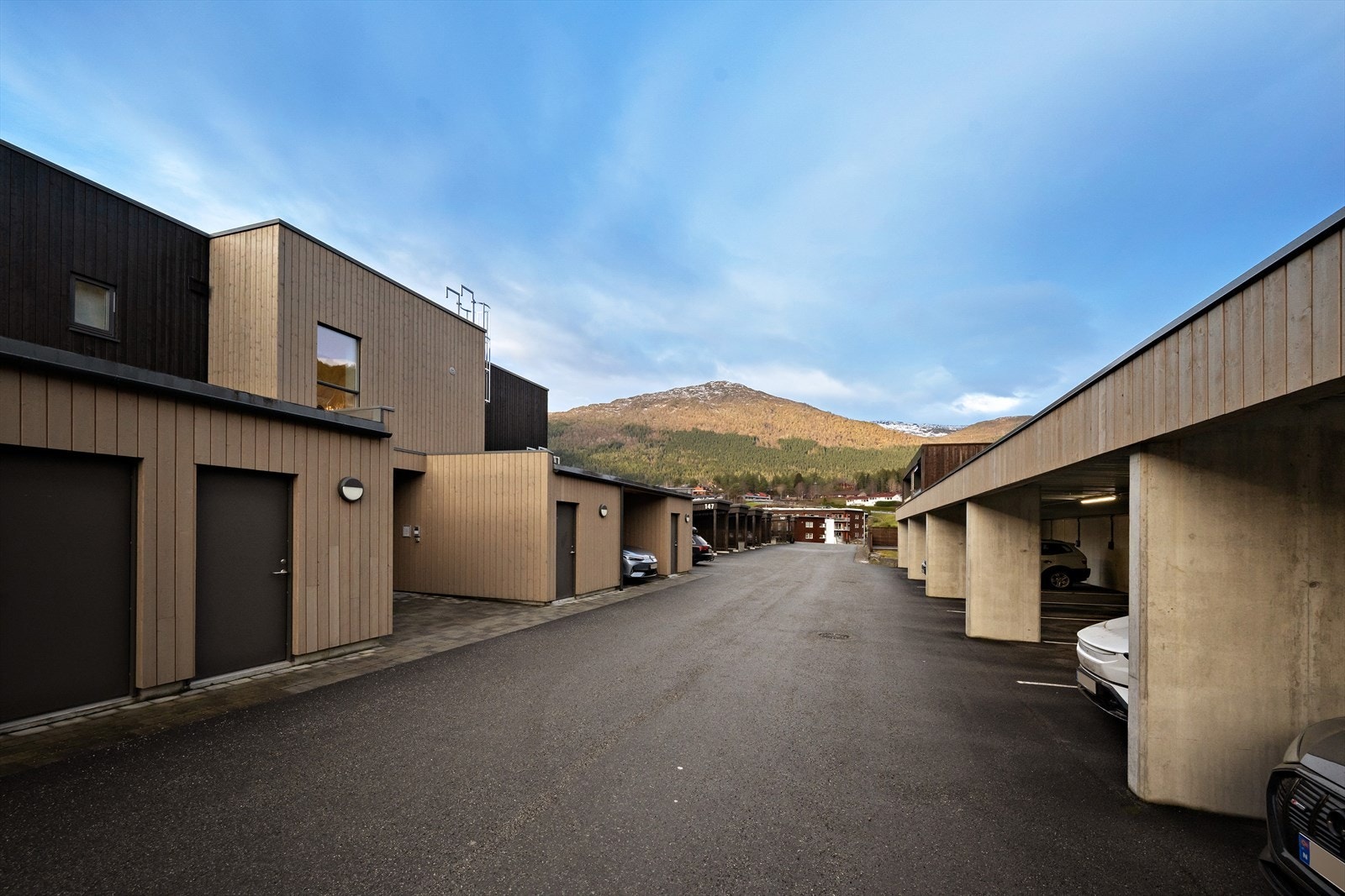 Parkering i carport like ved inngangspartiet til blokka. Det er tilrettelagt for montering av ladeboks til el-bil Galleribilde
