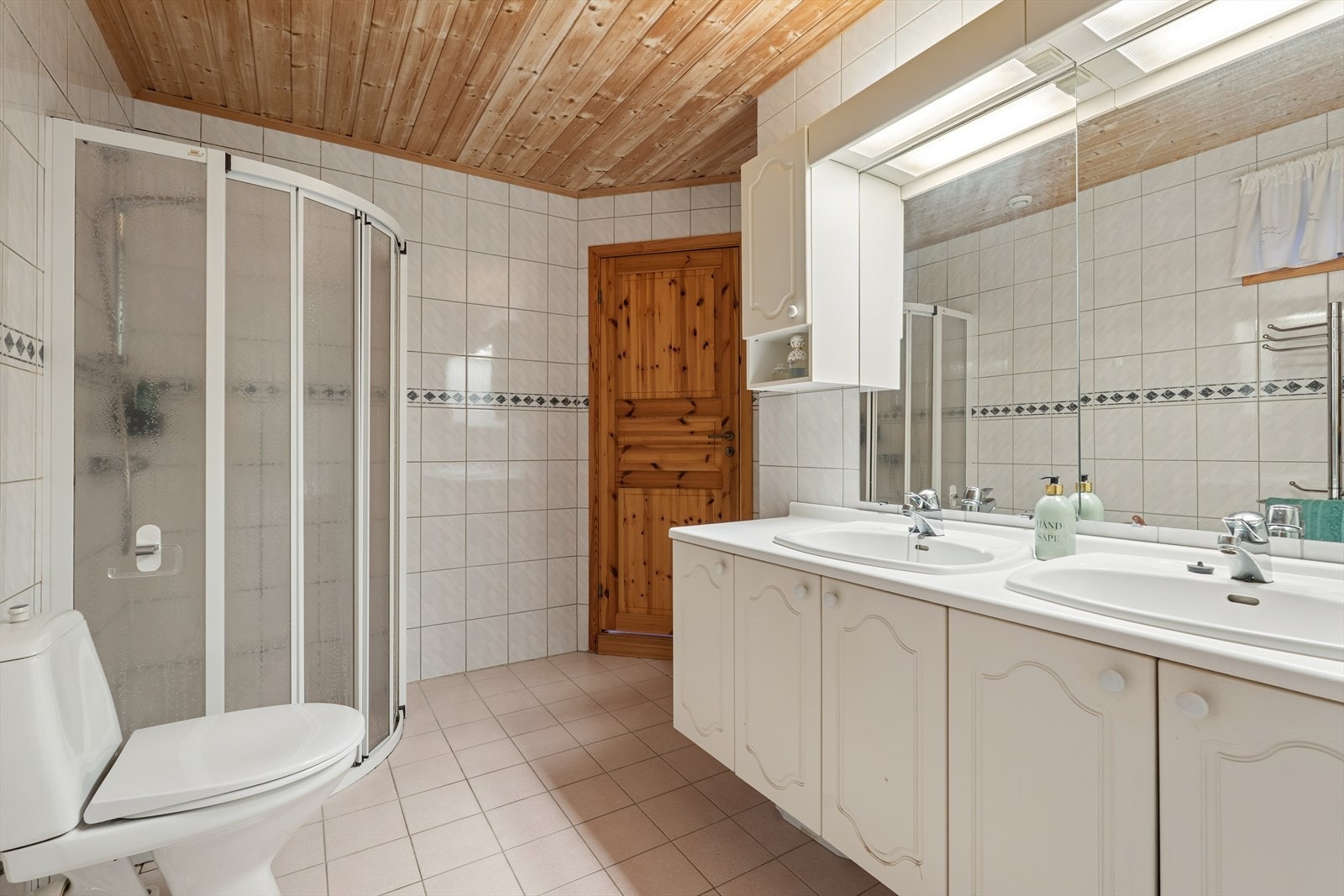 Badet har innredning med profilerte fronter med dobbeltservanter, dusjhjørne og klosett. Galleribilde