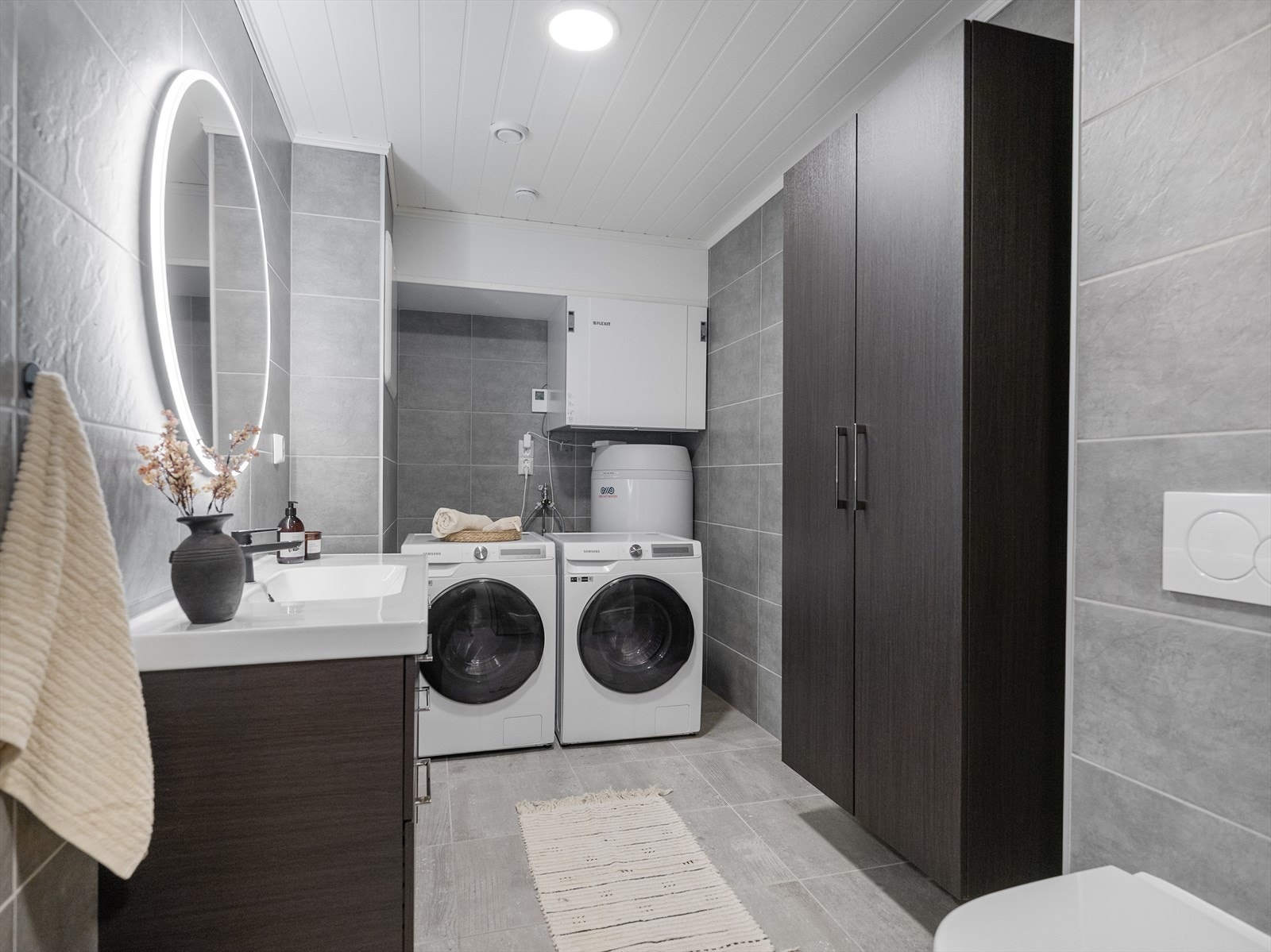 Delikat flislagt bad med god plass til vaskemaskin Galleribilde