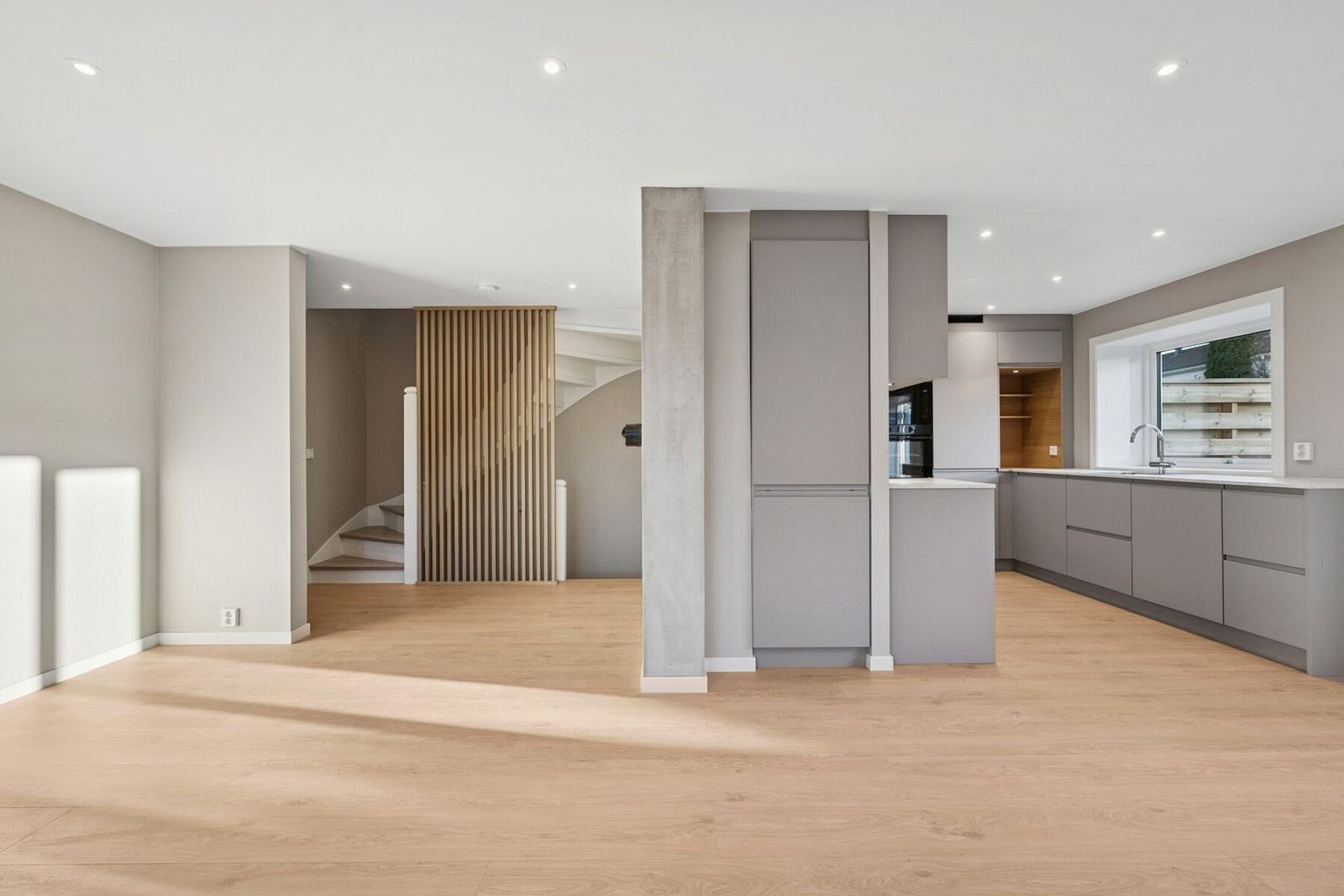 Åpen og luftig stue med delvis avskjermet kjøkkenløsning. Galleribilde