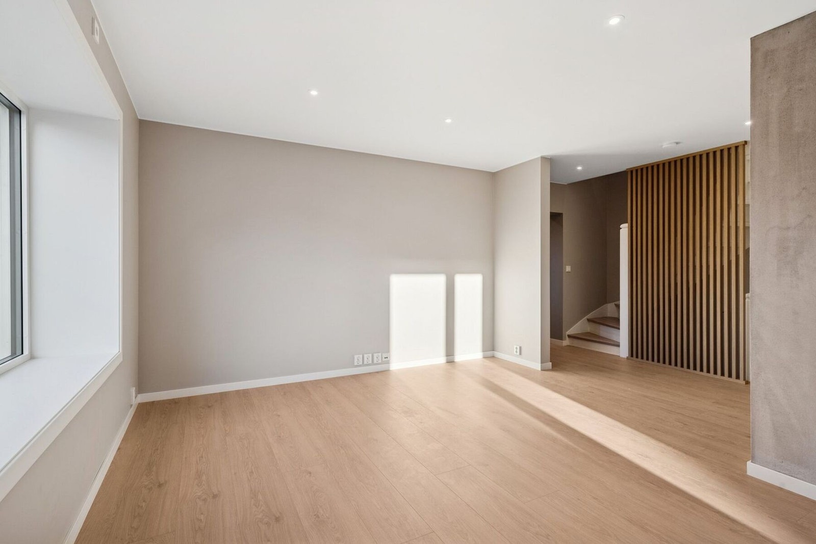 Romslig og lys stue med moderne uttrykk, store vinduer og gjennomgående god takhøyde. Galleribilde