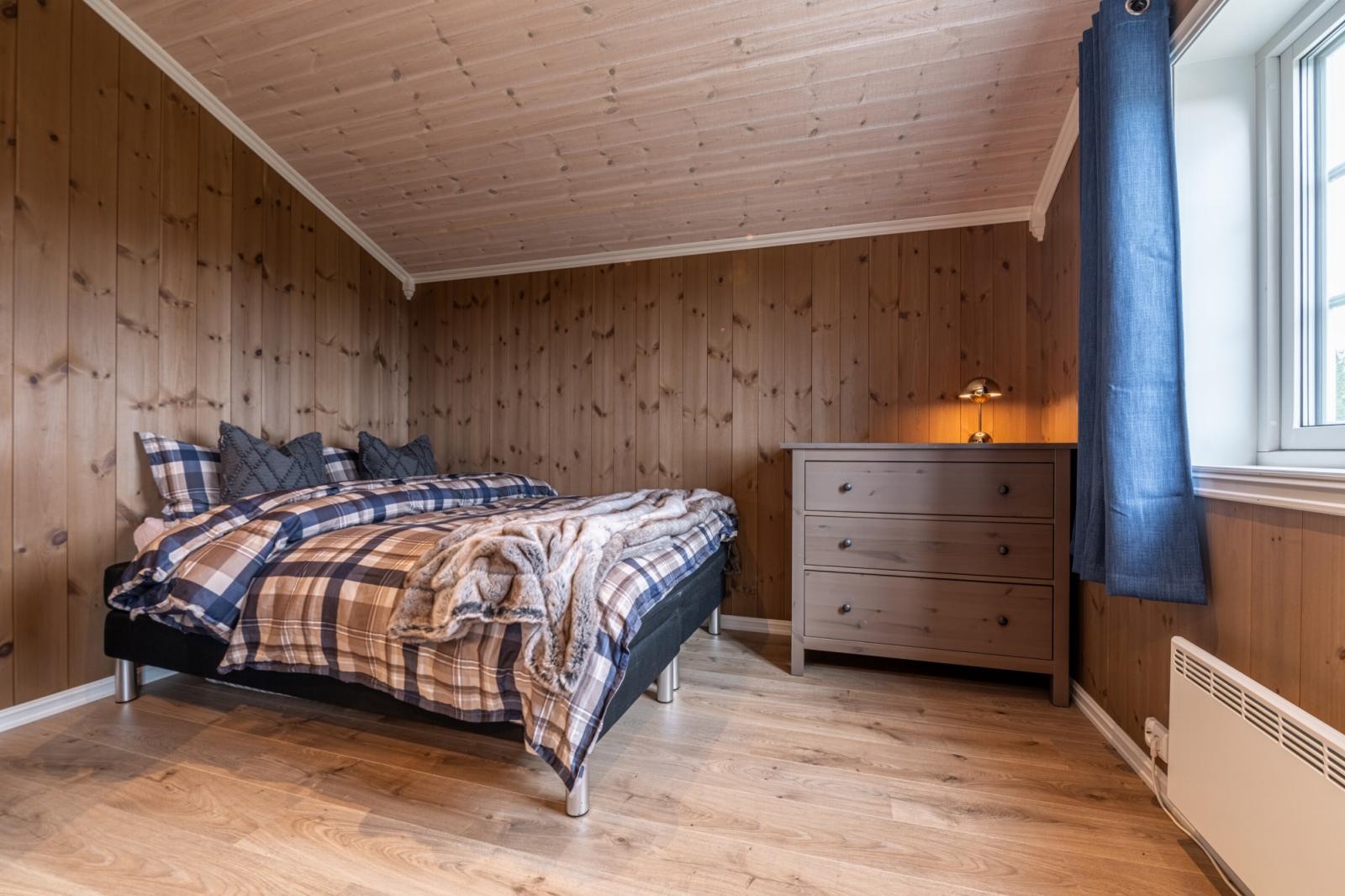 Koselig rom med skråtak, seng og kommode. Galleribilde