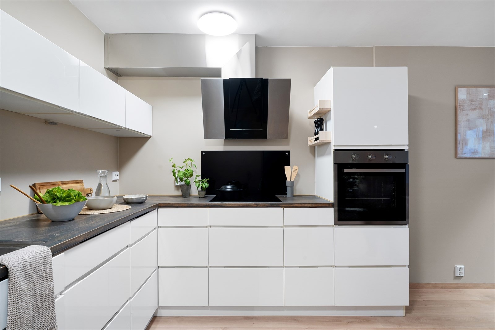 Hvit, moderne kjøkkeninnredning med god skap- og benkeplassø. Integrert stekeovn, induksjonstopp og oppvaskmaskin. Galleribilde