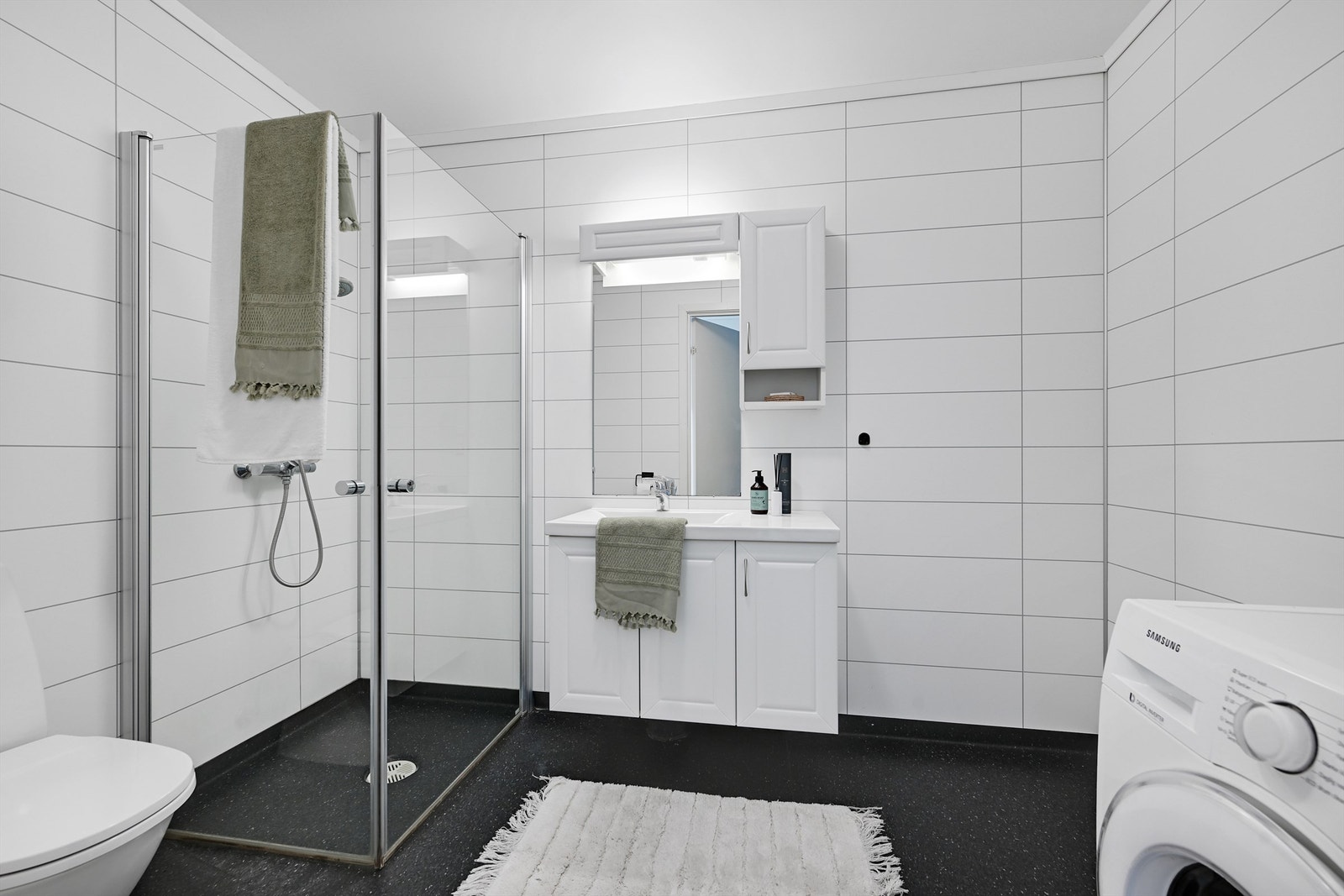 Leilighetens bad har innredet servant m/ speil, dusjhjørne, toalett, varmekabler i gulv og opplegg for vaskemaskin. Galleribilde