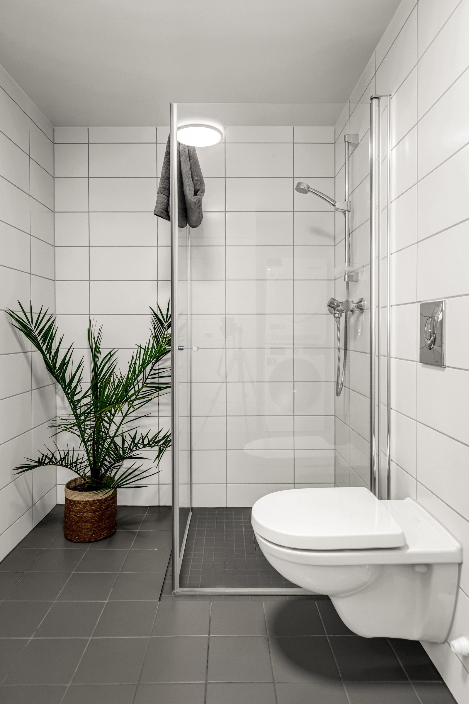 Badet er innredet med baderomsinnredning, servant, toalett og dusjhjørne med innfellbare glassdører. Galleribilde