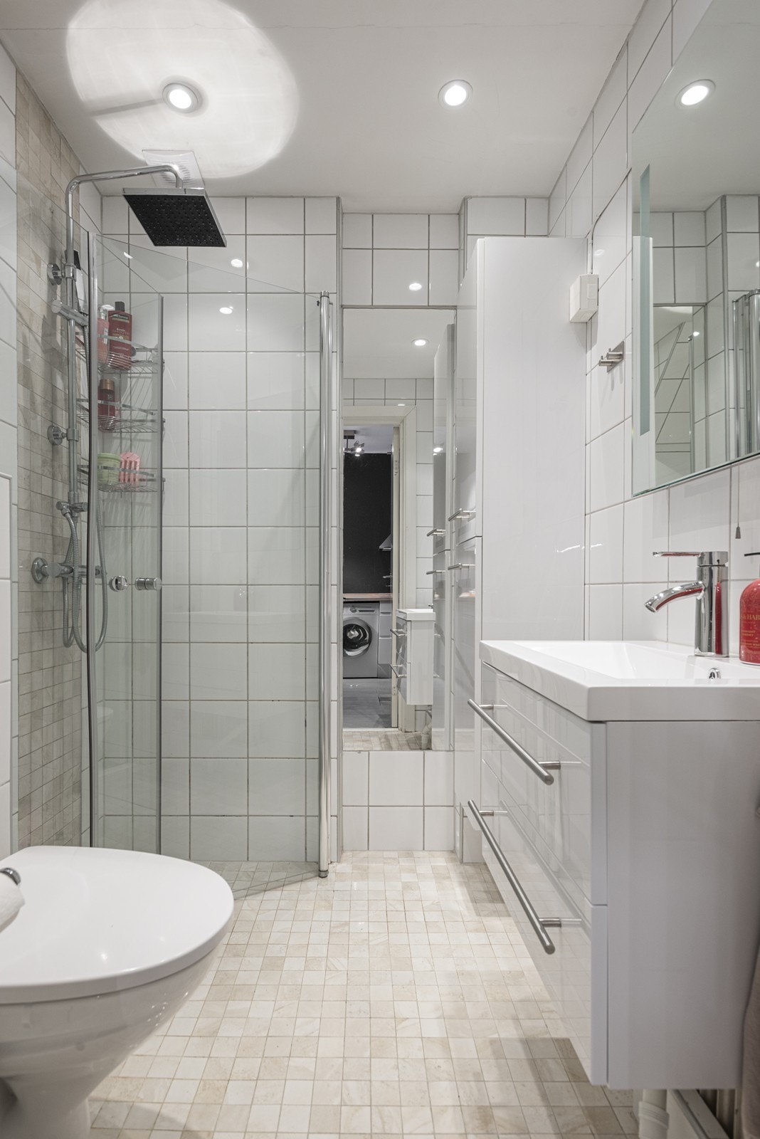 Tidløst bad med innredning bestående av mekanisk avtrekk, dusjhjørne, innfellbare dusjdører, servant, servantskap og veggmontert wc Galleribilde