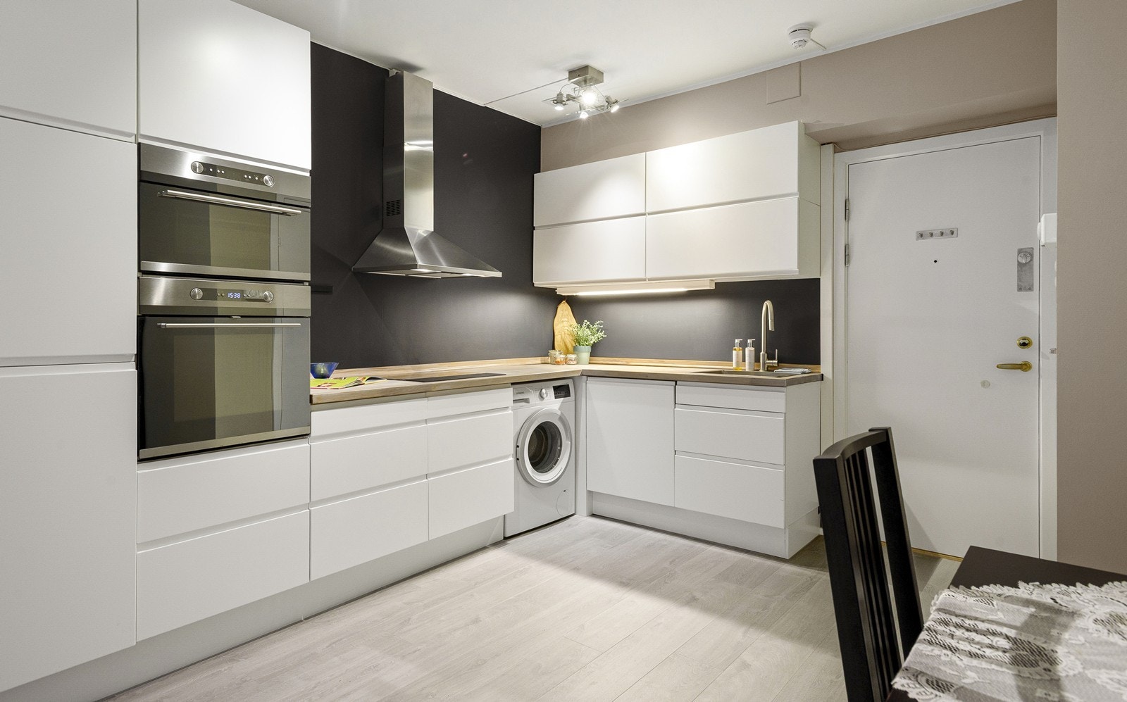 Stilfullt kjøkken med hvitmalt innredning og heltre eikebenkeplate. Kjøkkenet har opplegg for både oppvaskmaskin og vaskemaskin, samt en kullfiltervifte over stekesonen Galleribilde