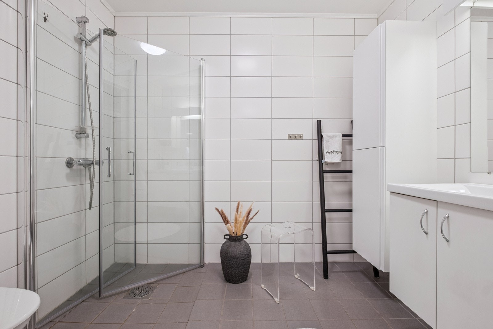 Lekkert, flislagt bad med toalett, dusjhjørne med glassdører, servant med skap samt veggskap. Galleribilde