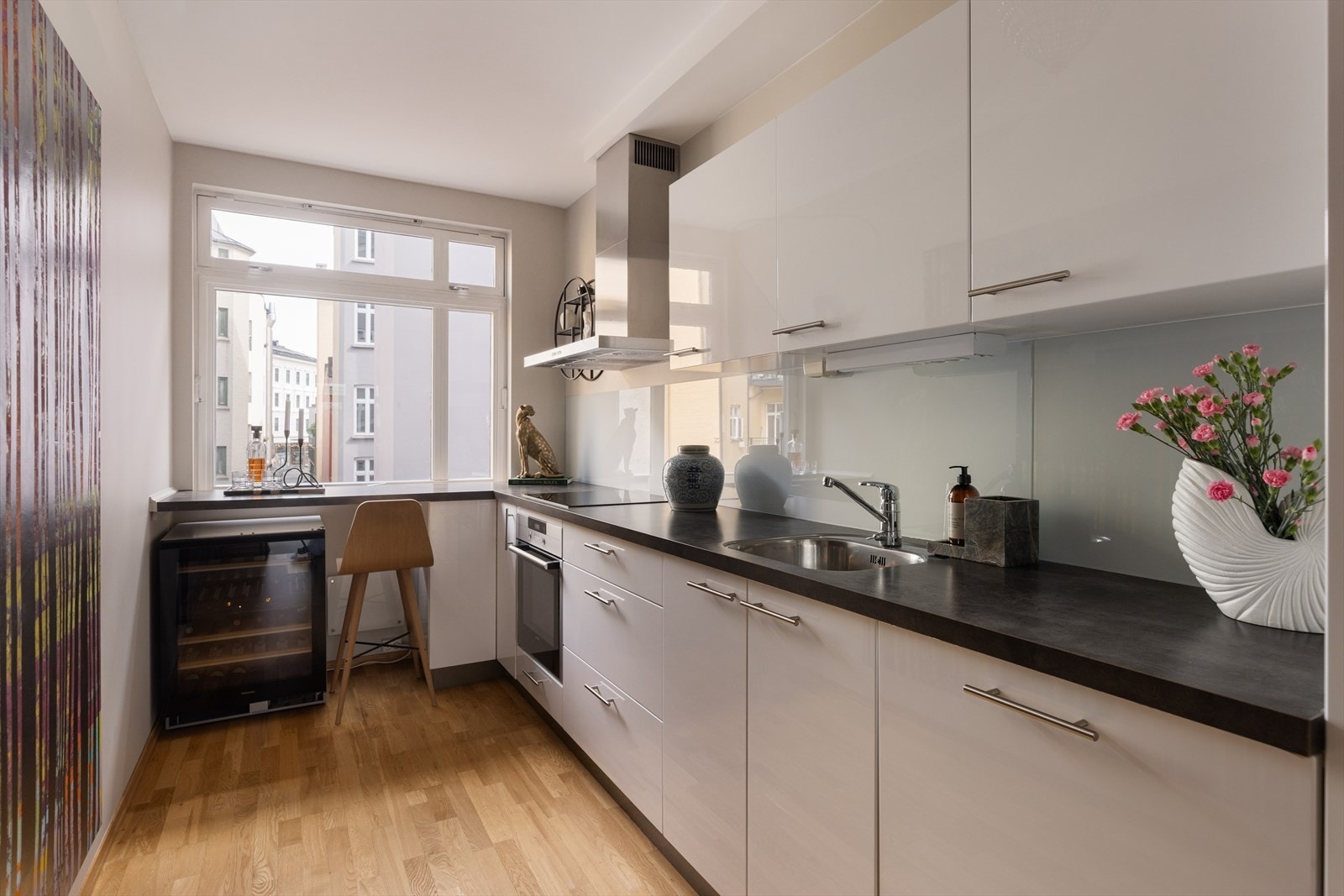 Moderne kjøkken utstyrt med integrert platetopp og stekovn, kjøleseskap, og oppvaskmaskin. Kullfiltervifte over stekesone og panelovn på vegg Galleribilde