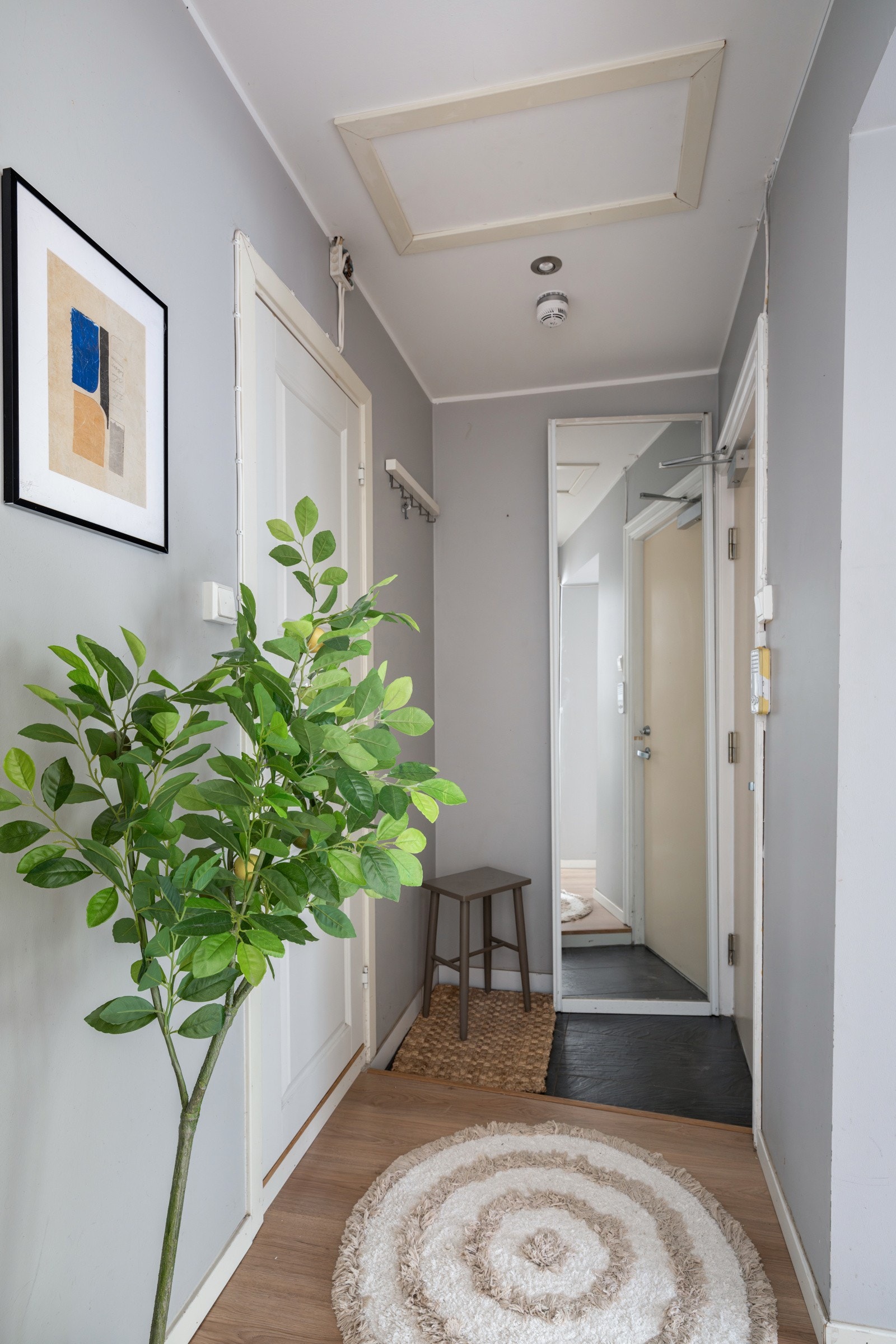 Entréen har nedfelt areal med mørke fliser, moderne enstavs laminat, glatte malte overflater og downlights i himlingen. Galleribilde