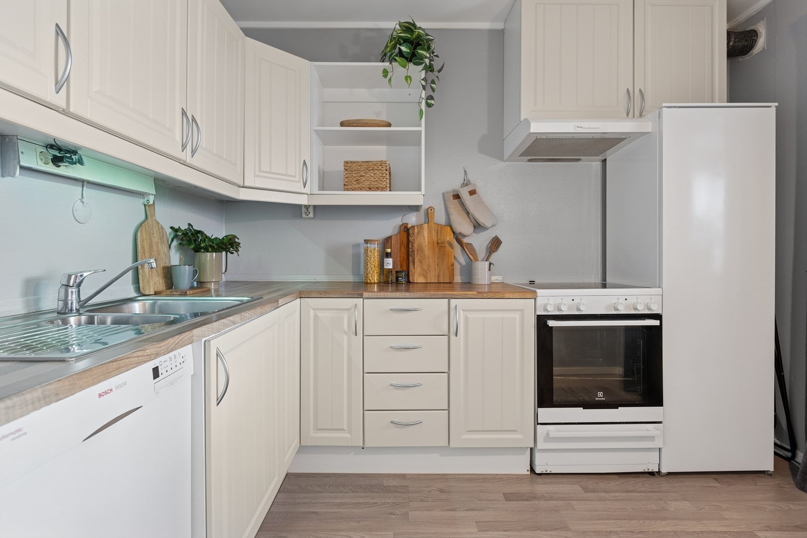 Innbydende hjørnekjøkken med lyse, profilerte fronter. Galleribilde