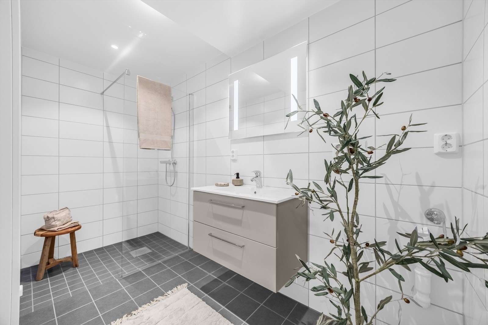 På bad i 1.etg er det innredning med servant på vegghengt servantskap. Vegghengte dusjdører i glass. Opplegg for vaskemaskin. Galleribilde