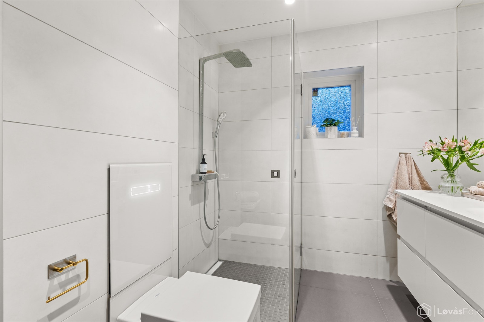 Vegghengt toalett og dusjnisje med regnfallsdusj og plassbesparende dører i herdet glass. Galleribilde