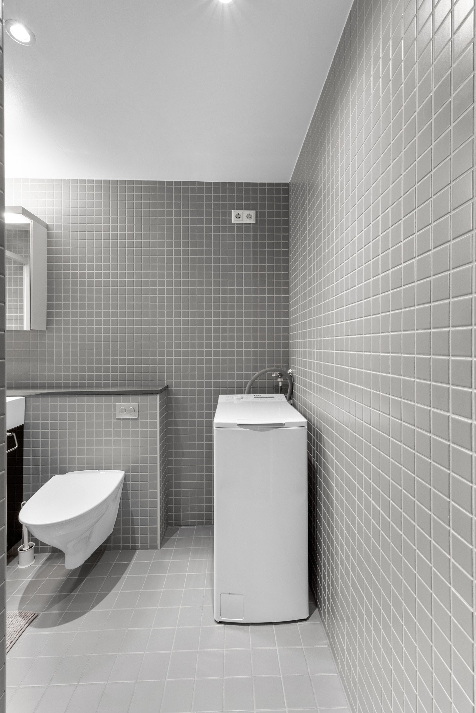 Rommet har servant, overskap med speil, dusjhjørne, vegghengt toalett og opplegg for vaskemaskin. Galleribilde