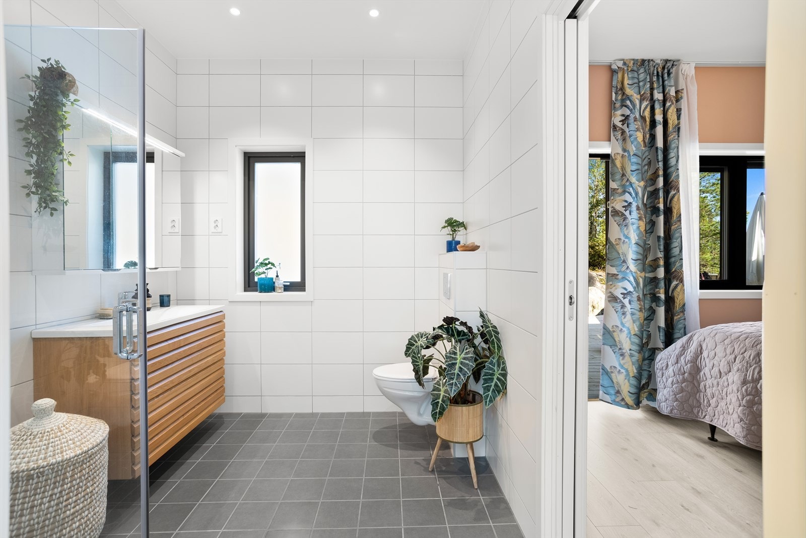 Badet er innredet med servantskap med en overliggende servant, speil, toalett og dusjhjørne med innfellbare dører. Galleribilde