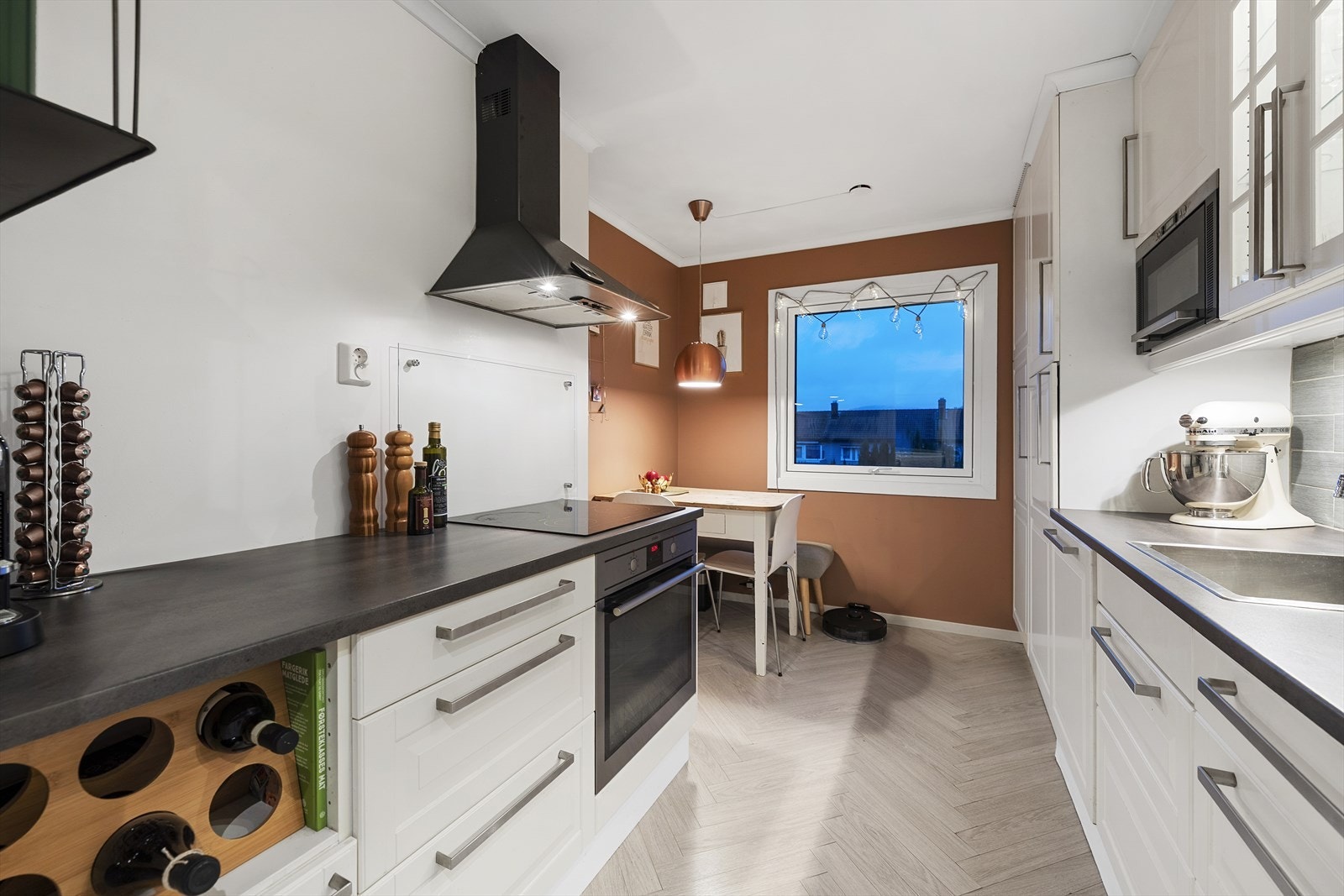 Lyst og tiltalende kjøkken med hvite, profilerte fronter og laminert benkeplate Galleribilde