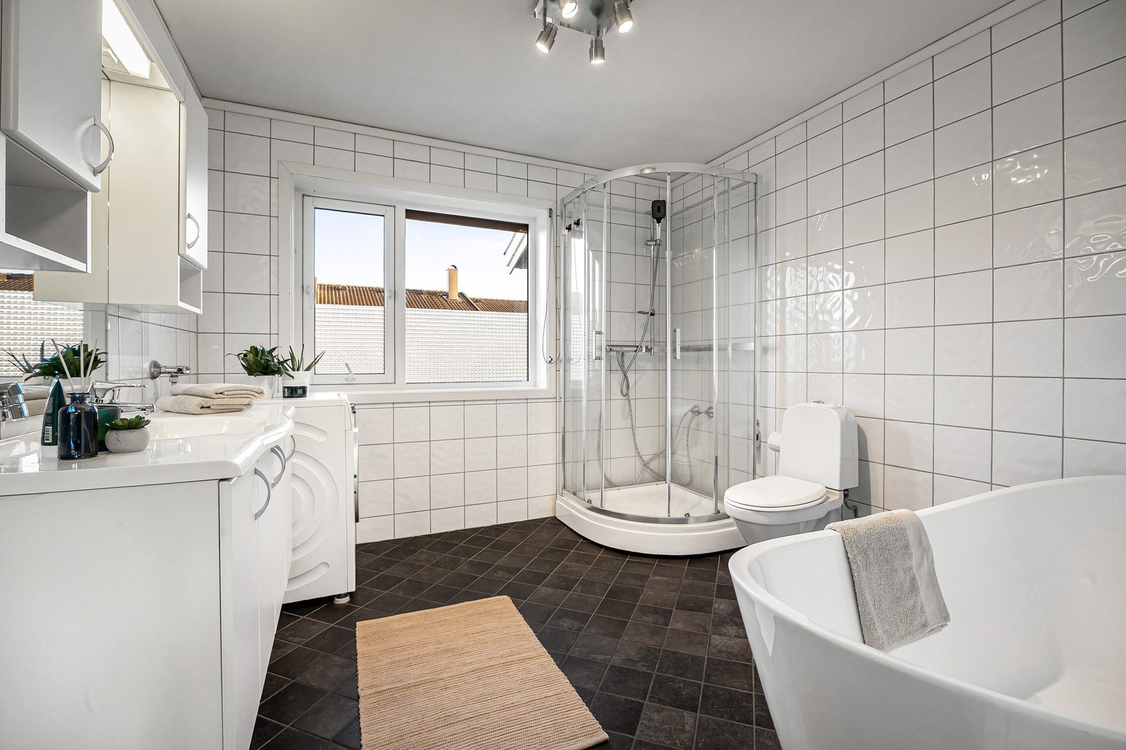 Stort flislagt bad med romslig servantinnredning og gulvstående toalett Galleribilde