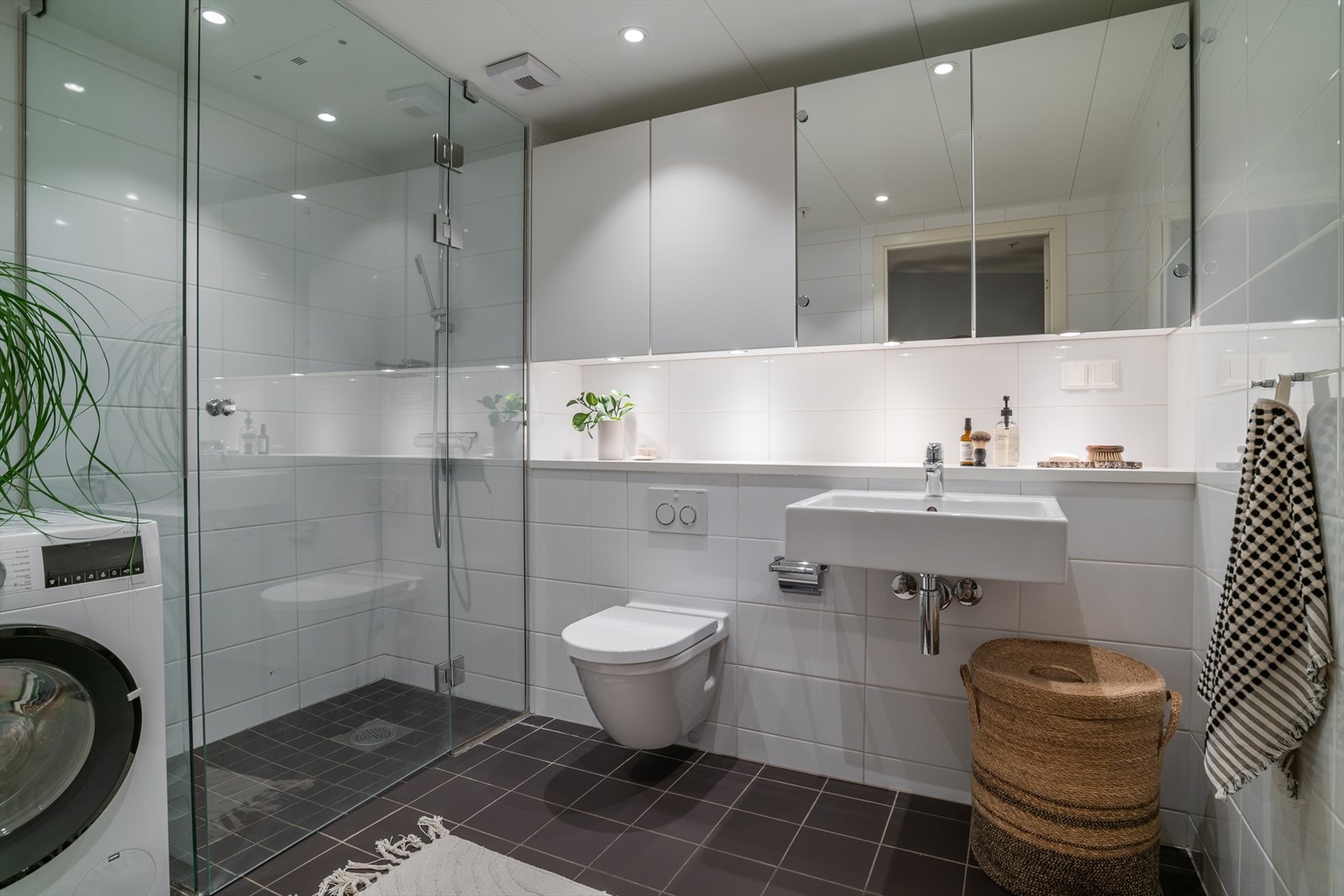 Pent flislagt og romslig bad med dusjdører i herdet glass og opplegg for vaskemaskin. Galleribilde