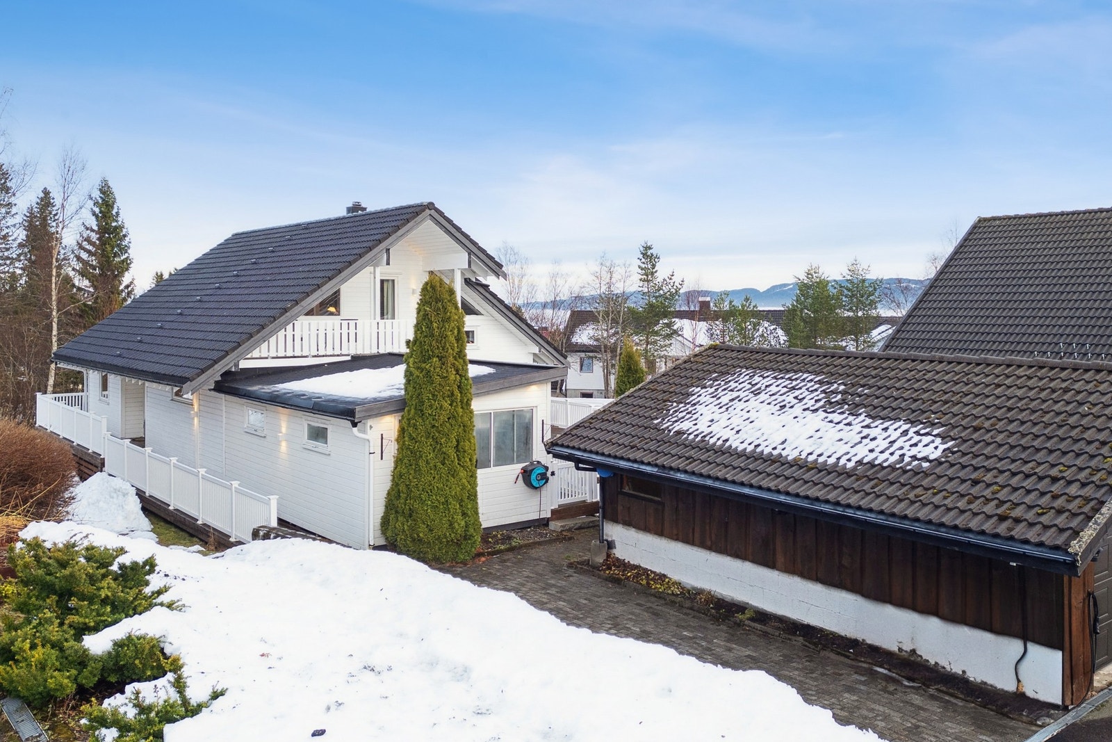 Det er godt med plass til parkering på steinlagt innkjørsel, samt en parkeringsplass i delt garasje med naboen. Galleribilde