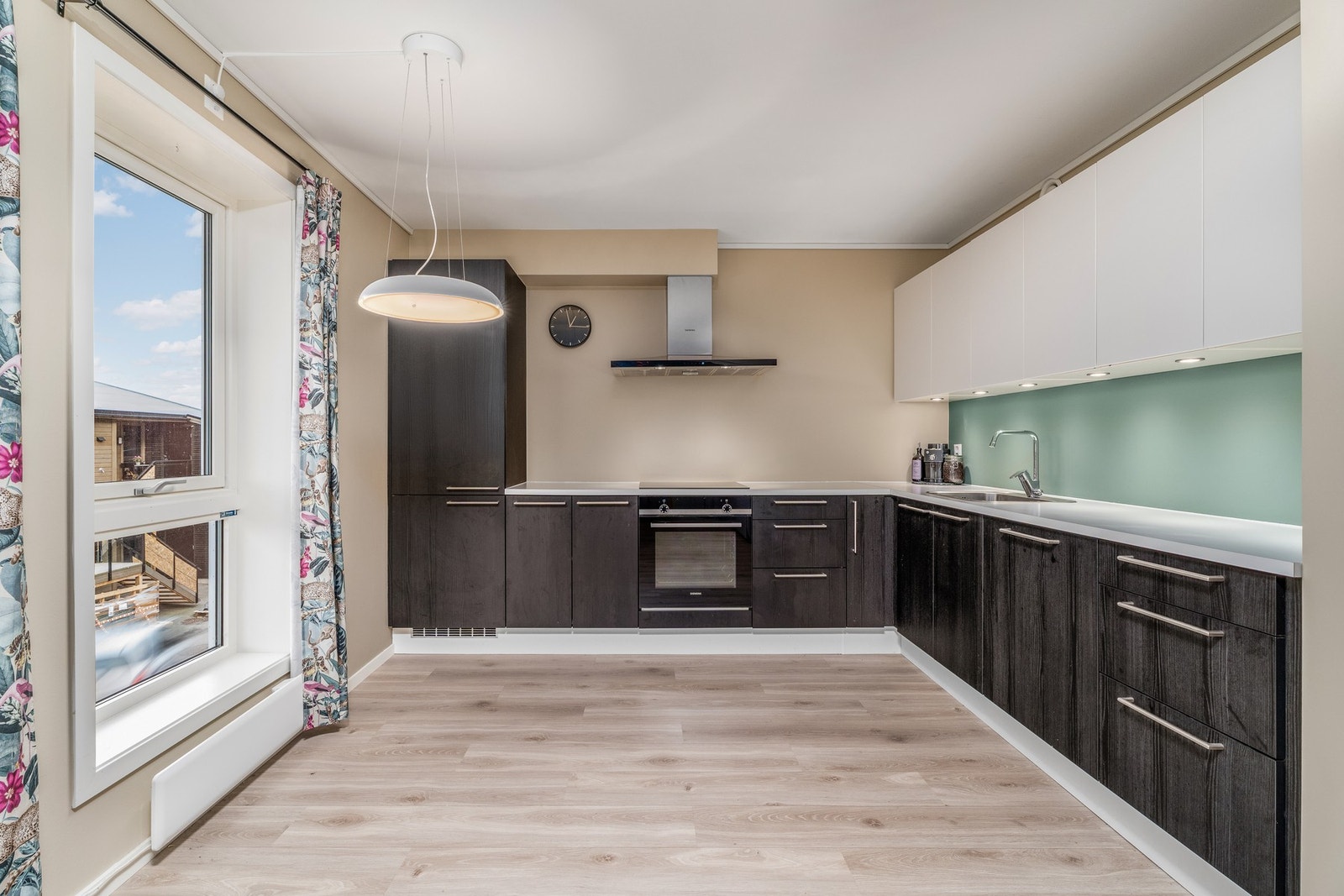 Flott kjøkken fra kvalitetsleverandøren HTH med mørke, glatte fronter og benkeplate av laminat. Legg merke til benkebelysningen i overskapene. Galleribilde