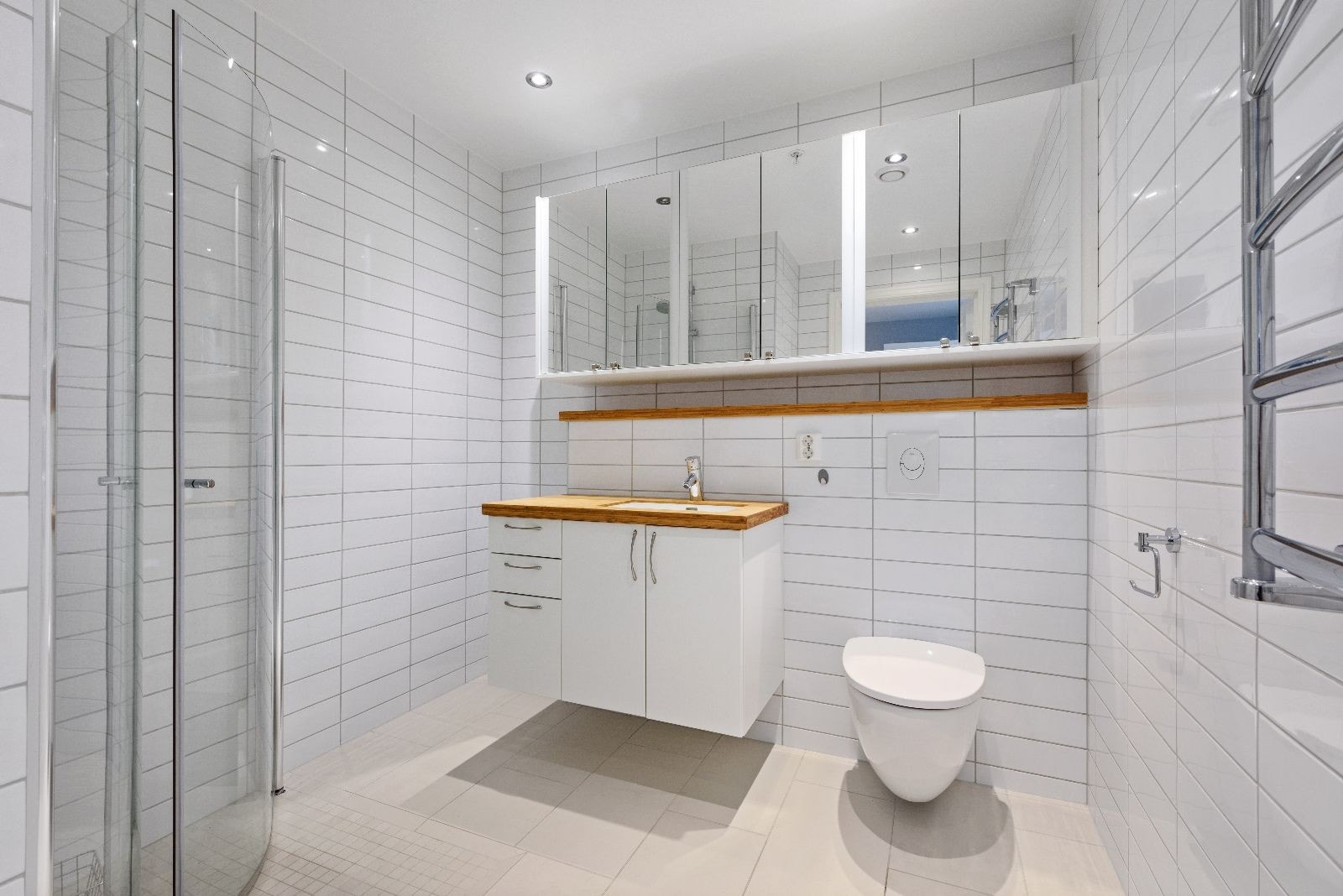 Delikat og moderne flislagt bad med varme i gulv, dusj, servant og toalett. Galleribilde