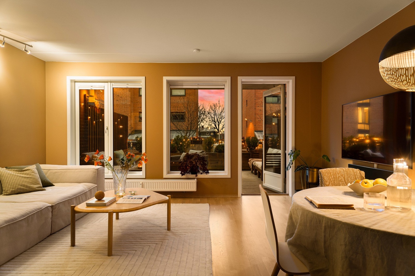 Lys og luftig stue i åpen løsning mot kjøkkenet, hvor store vindusflater slipper inn rikelig med naturlig lys og skaper en behagelig atmosfære gjennom hele dagen. Galleribilde