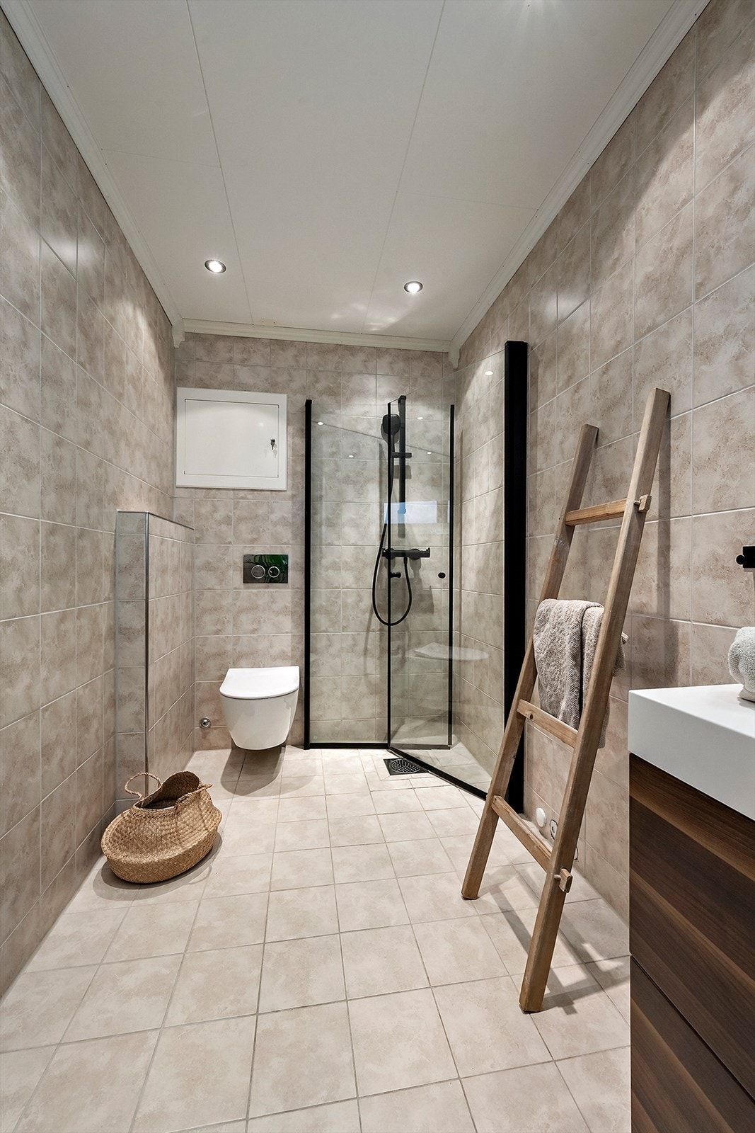 Badet har veggfestet WC, innfellbare dusjvegger dusjbatteri og baderomsinnredning med servant. Galleribilde