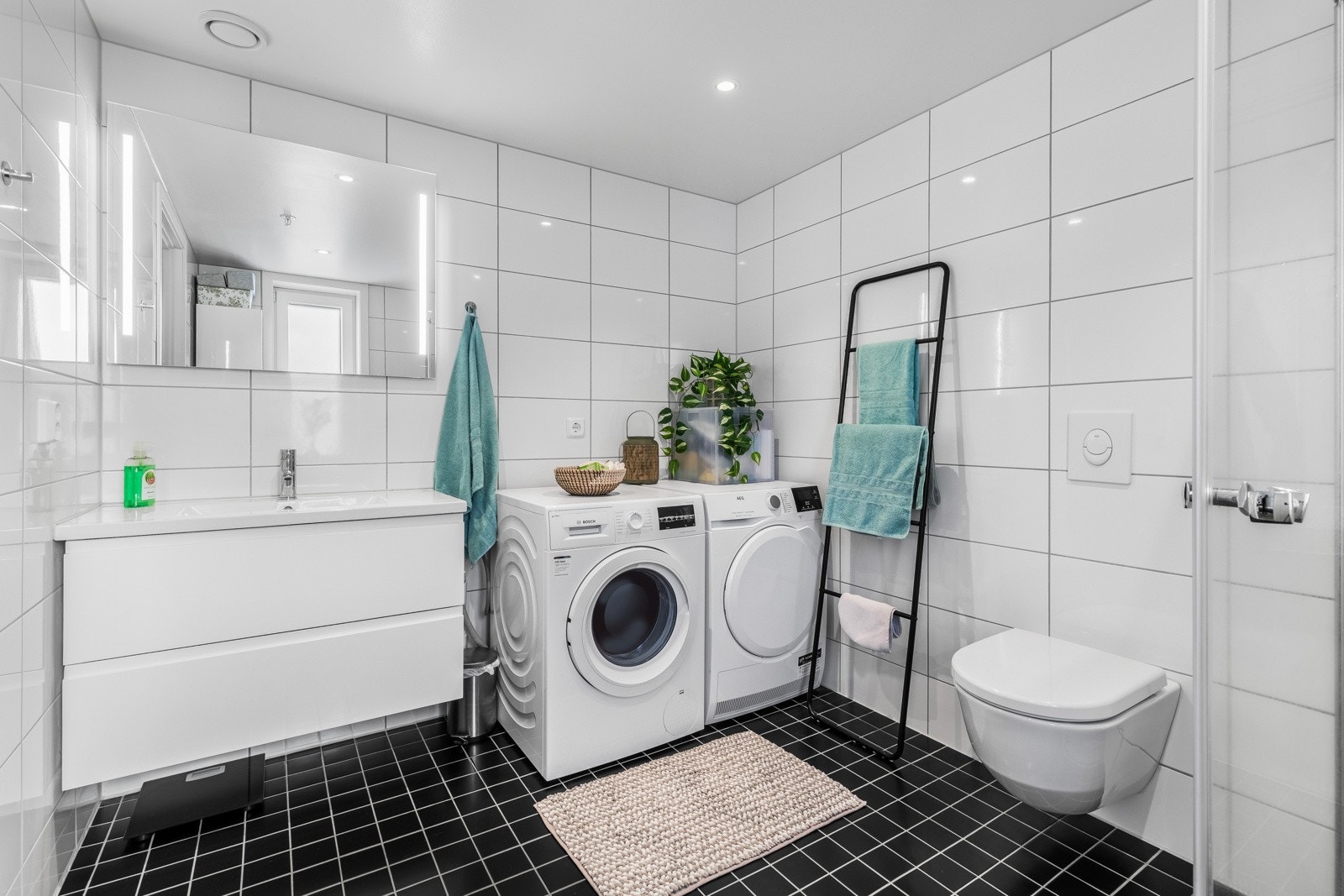 Badene i leiligheten er flislagt på både gulv og vegger, noe som gir en ren og helhetlig estetikk. Med lys fra vinduer og godt plasserte lyskilder, får du et lyst og behagelig rom. Galleribilde