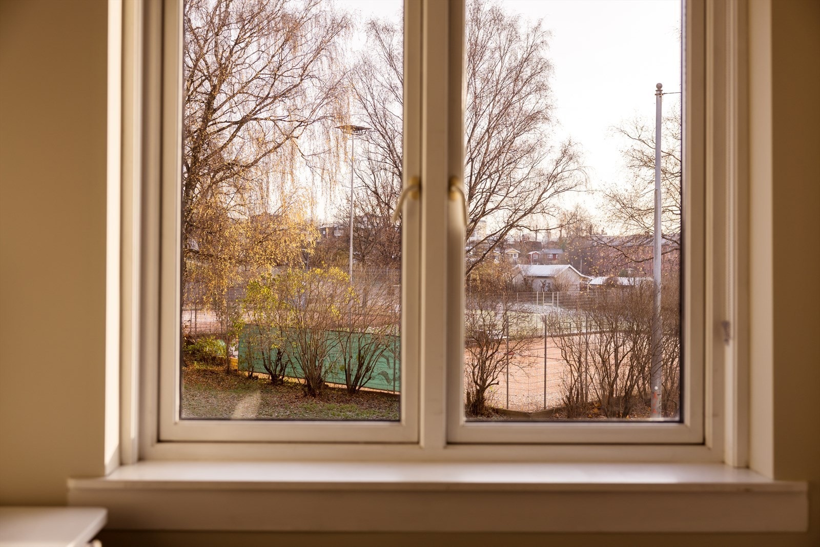 Utsyn fra vindu mot trær og stille nærområde. Galleribilde