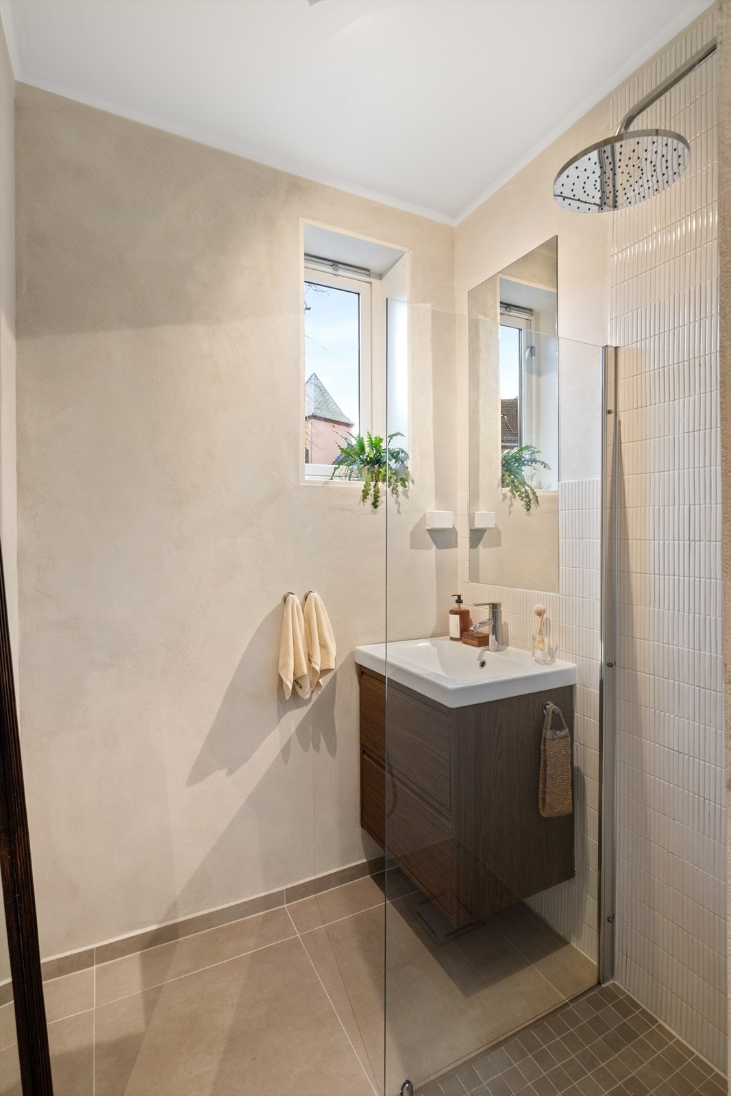 Baderommet er innredet med vegghengt klosett, servant nedfelt i innredning, speil og dusjhjørne med svingbare glassdører. Galleribilde