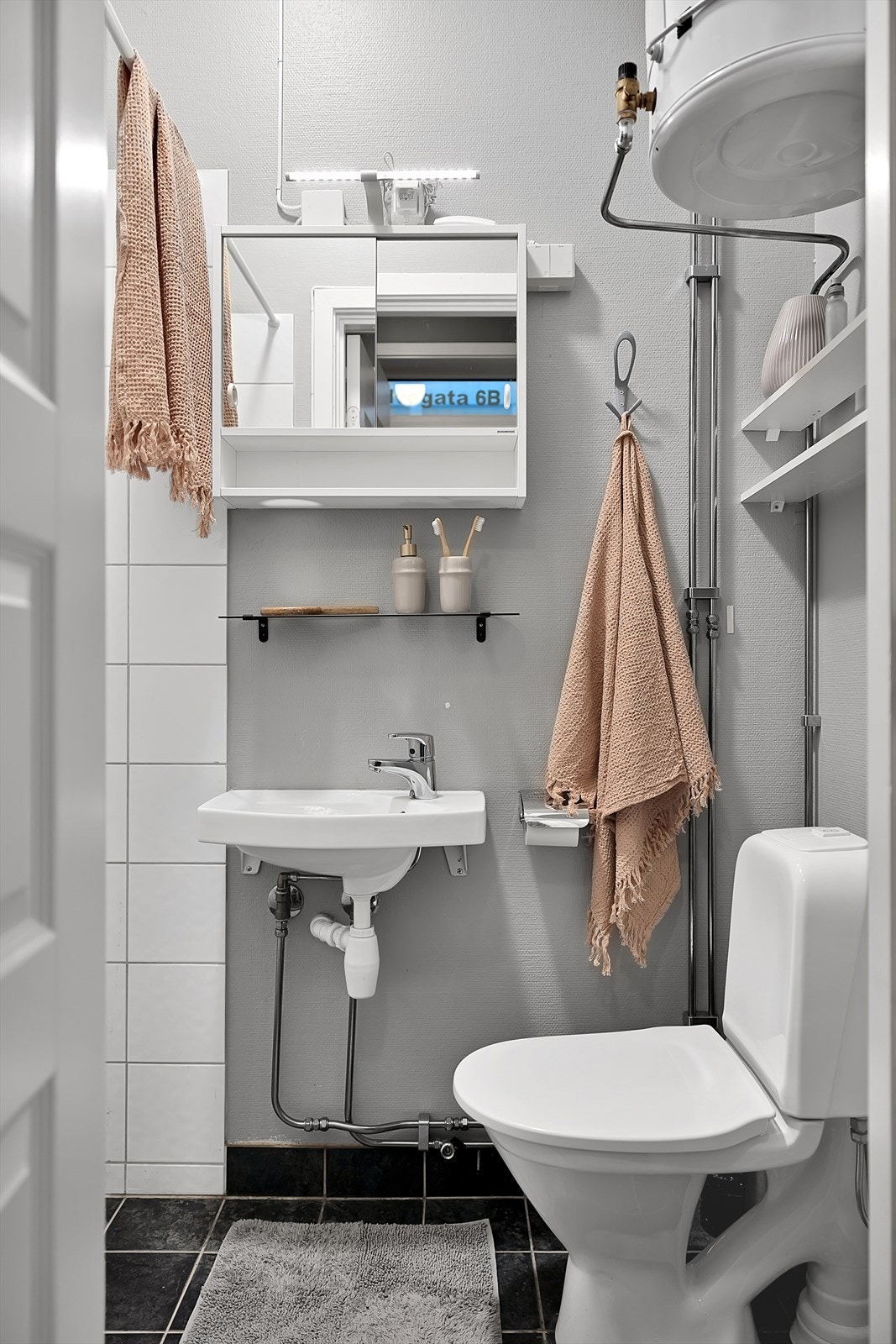 Servant på vegg. Speilskap med lys over. Dusjhjørne - garnityr på vegg. Gulvstående toalett. Galleribilde