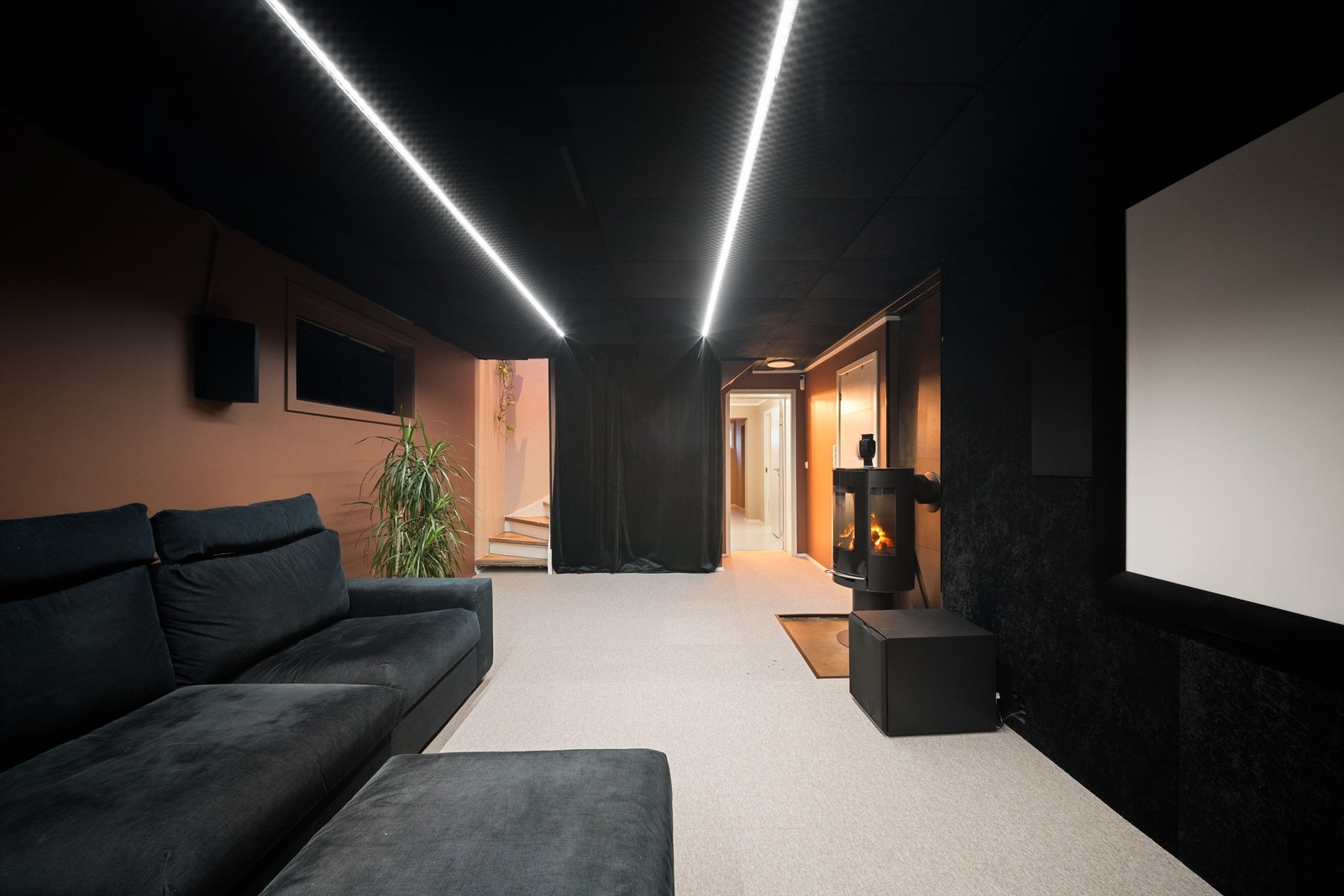 TV-stuen er stilfull etter oppussing. Himlingen og dels veggene har akustikk-dempende overflater. Heldekkende teppe er lagt på gulvet. Ildstedet er også av nyere dato. Galleribilde
