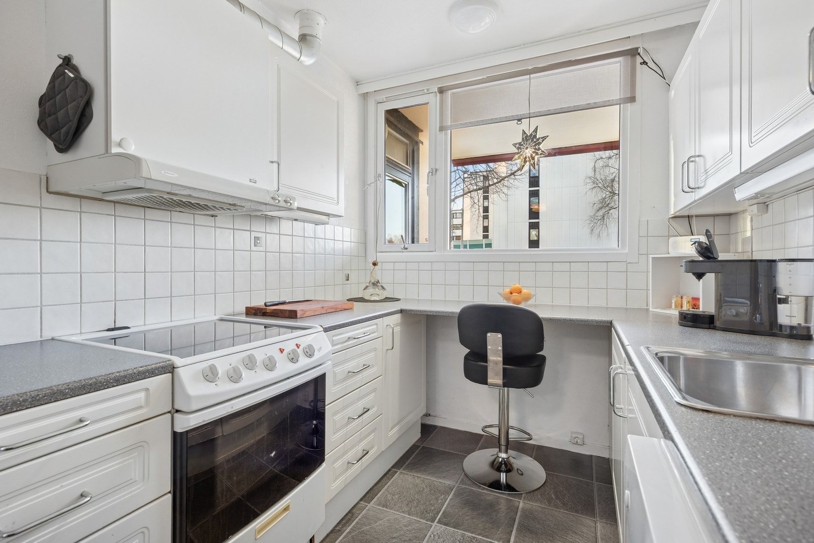 Det er fliser mellom kjøkkenbenk og overskap, som både er praktisk og gir et ryddig uttrykk. Galleribilde