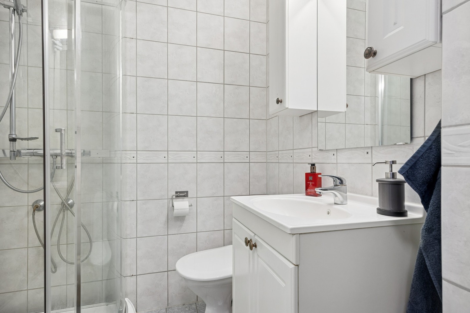 Innredning med vegghengt servantinnrednin, speil med overlys, praktisk dusjkabinett, samt vegghengt skap som gir praktisk oppbevaringsplass. Galleribilde