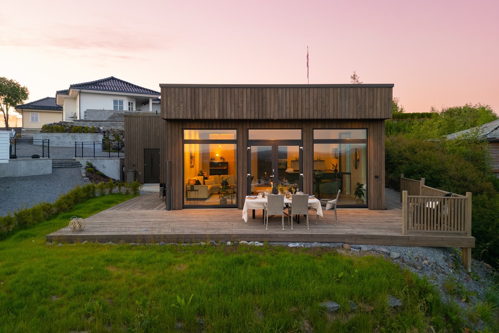 Moderne enebolig på ett plan med flott treverk, store vinduer og romslig terrasse. Galleribilde