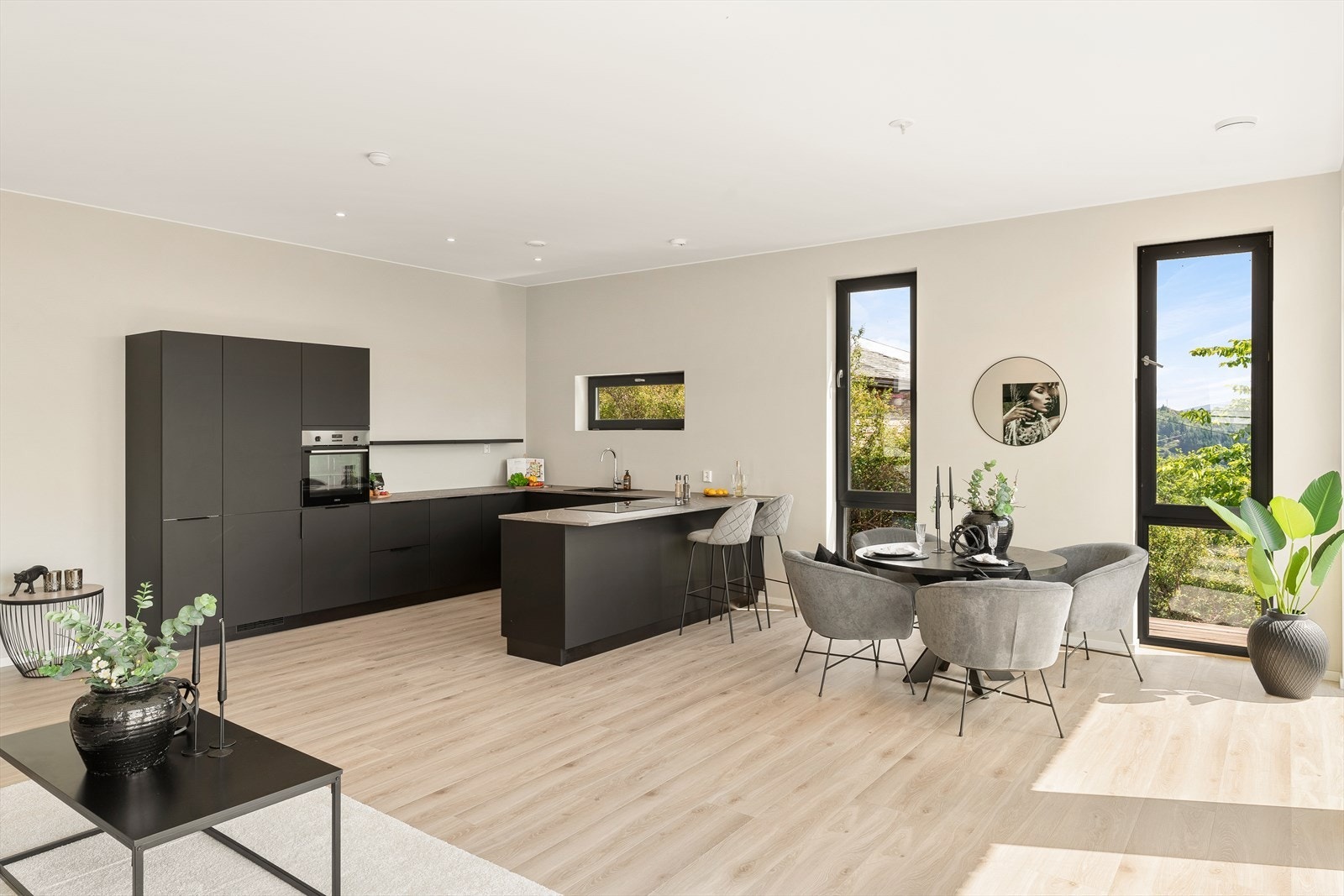 Moderne åpen stue-kjøkkenløsning med store vinduer som slipper inn rikelig med naturlig lys og viser den vakre utsikten. Galleribilde