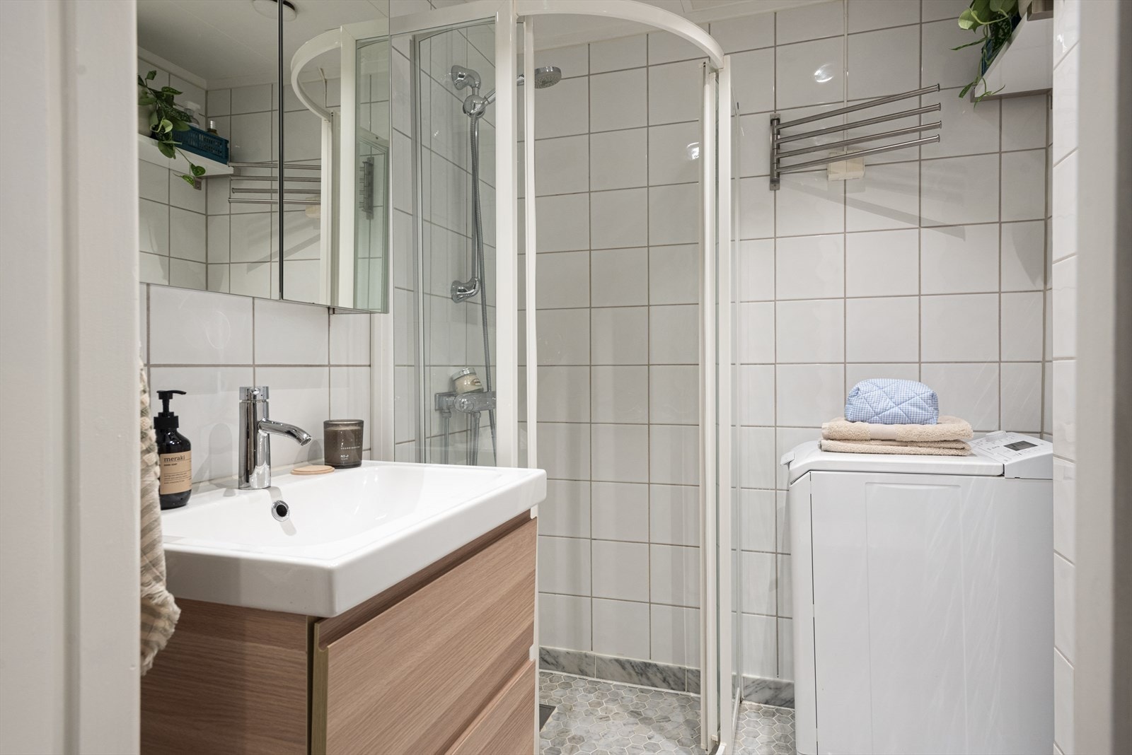 Badet er utstyrt med gulvstående wc, servantskap med glatte skuffefronter, overlimt servant med ettgreps armatur og speilskap på vegg. Galleribilde